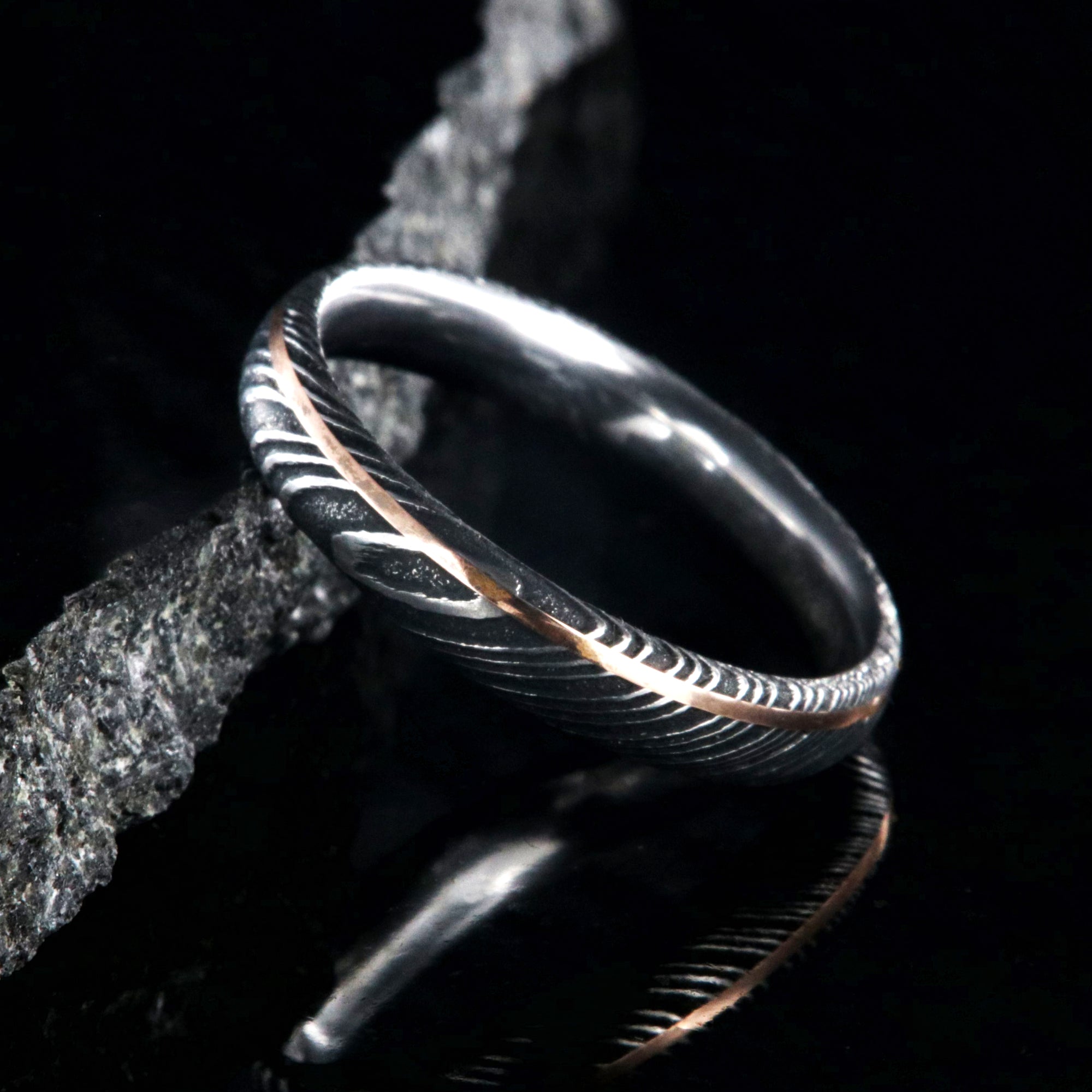 4mm wide black Damascus steel ring with ultra thin rose gold off-center inlay with polished inside