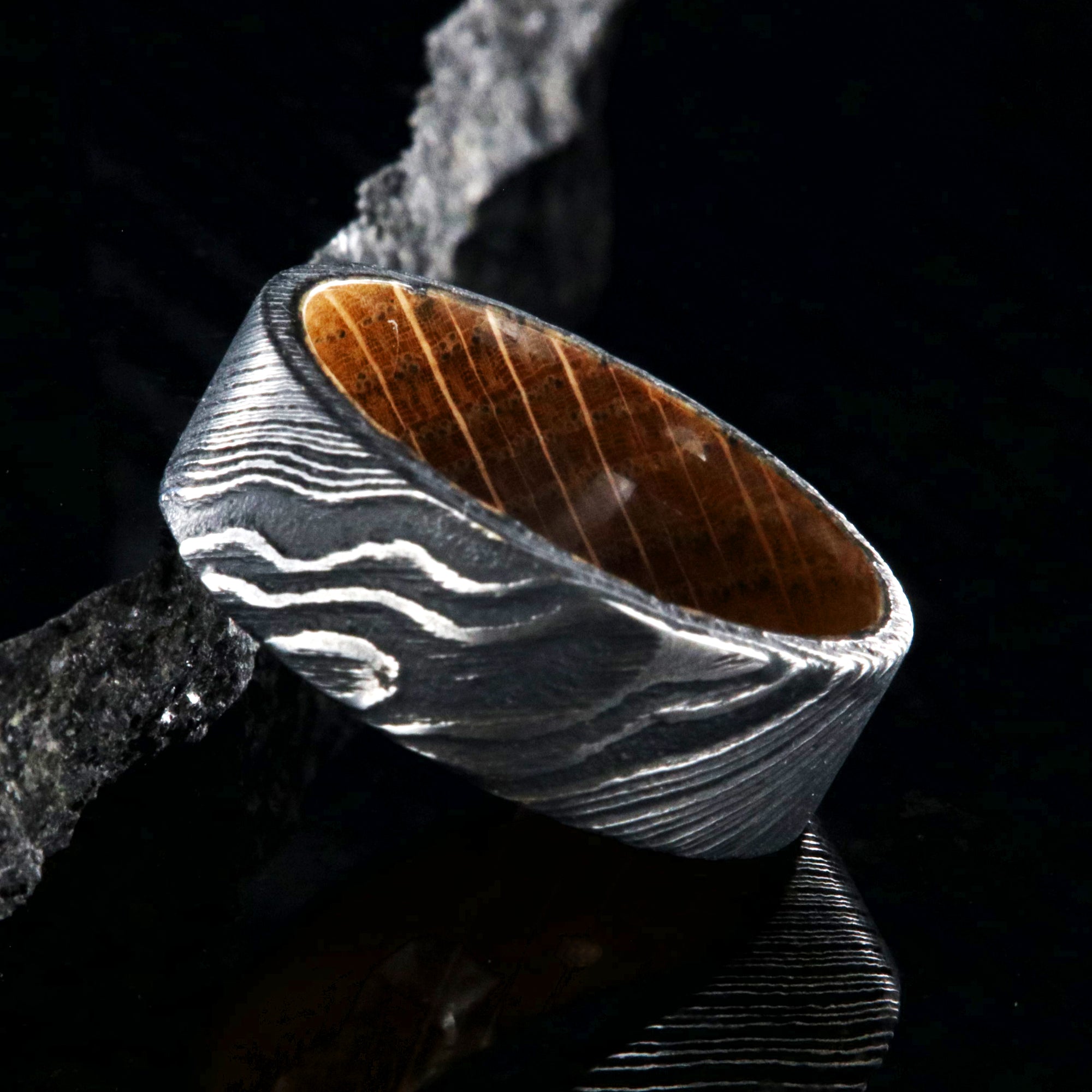 8mm wide black Damascus steel ring with flat profile and a Jack Daniel's whiskey barrel sleeve