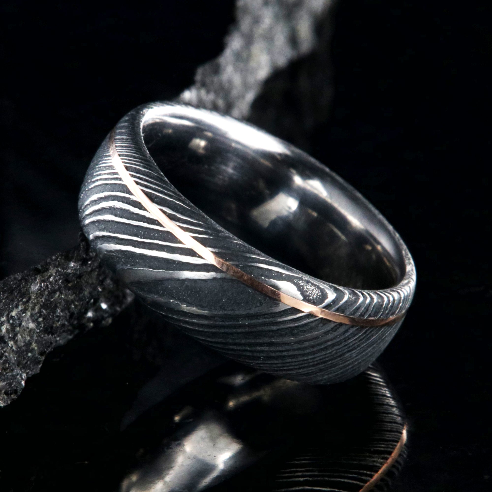 8mm wide black Damascus steel wedding band with an ultra-thin rose gold inlay