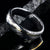 6mm wide black Damascus steel ring with polished inside and a thin off-center yellow gold inlay