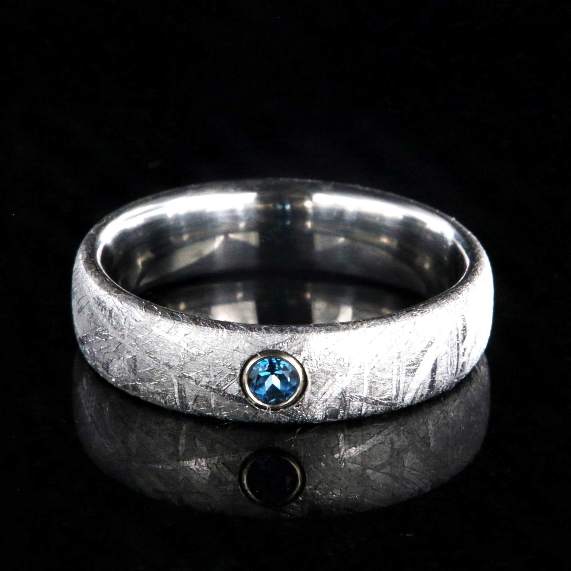 5mm wide women's meteorite ring with a blue topaz set in 14k gold bezel