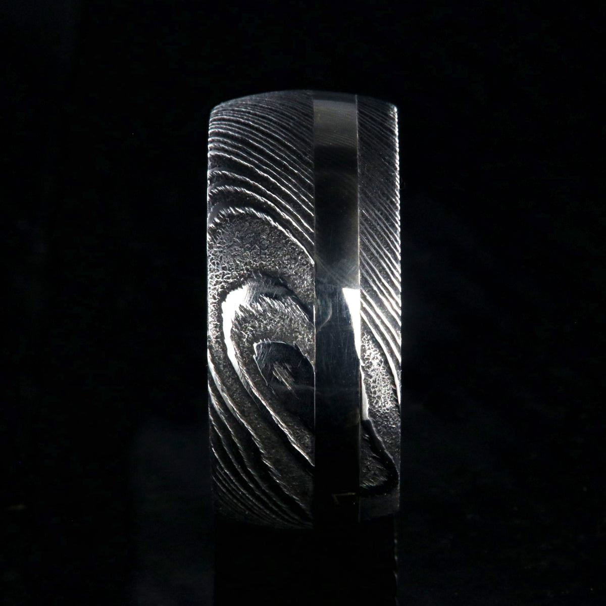 1mm wide black Damascus steel wedding band with a 2.5mm wide white gold inlay and white gold sleeve