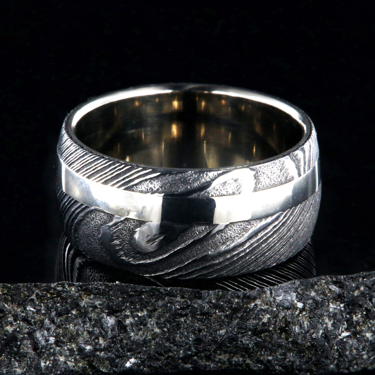 1mm wide black Damascus steel wedding band with a 2.5mm wide white gold inlay and white gold sleeve