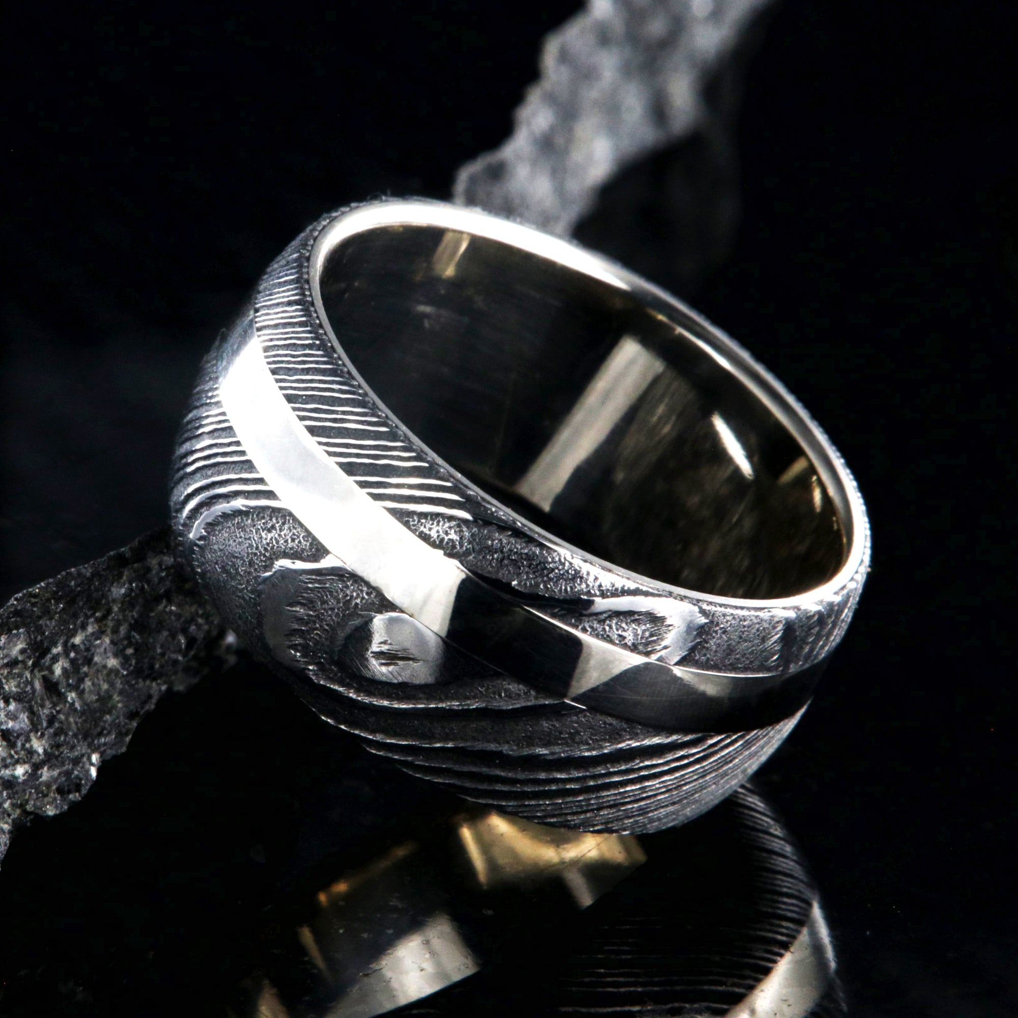 1mm wide black Damascus steel wedding band with a 2.5mm wide white gold inlay and white gold sleeve