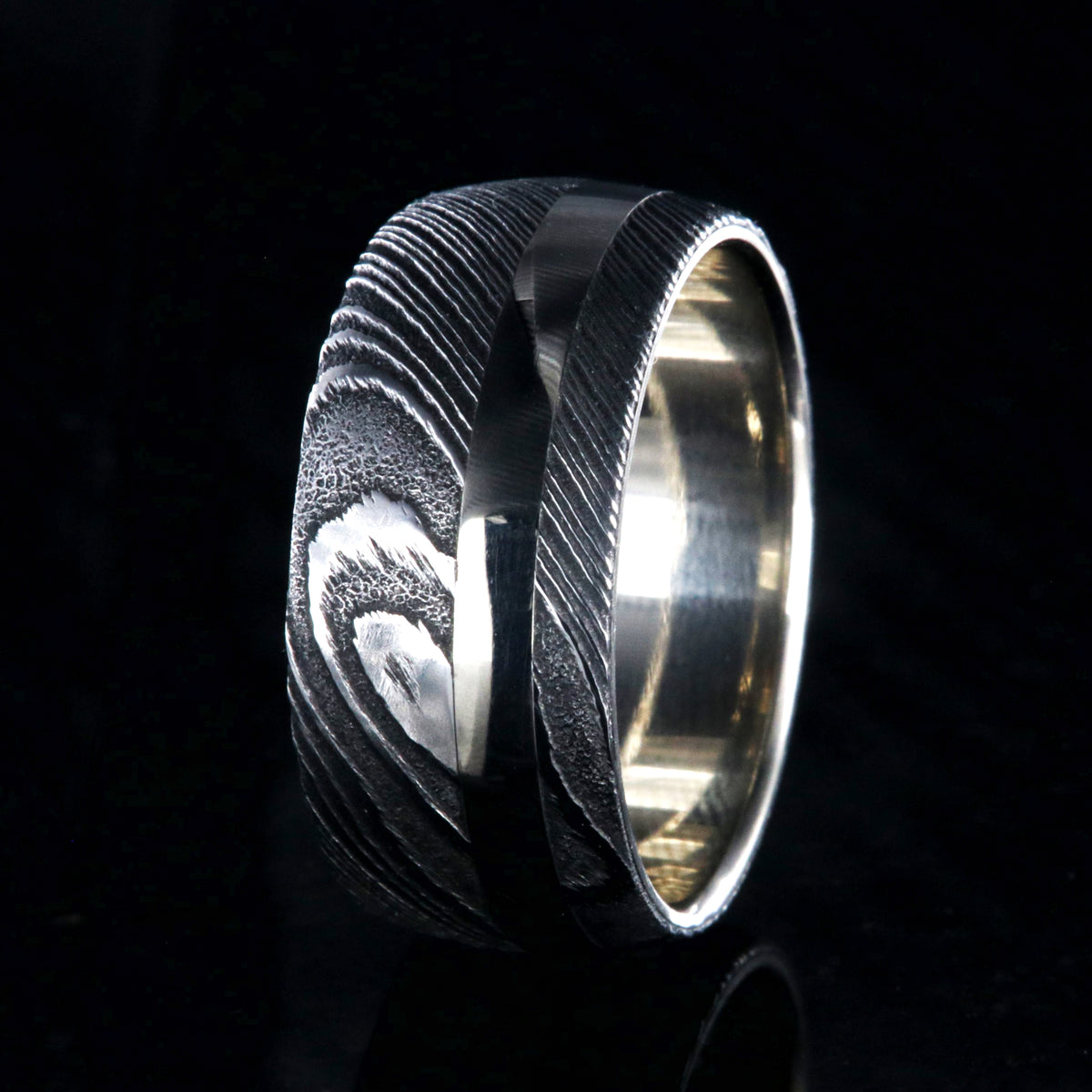 1mm wide black Damascus steel wedding band with a 2.5mm wide white gold inlay and white gold sleeve
