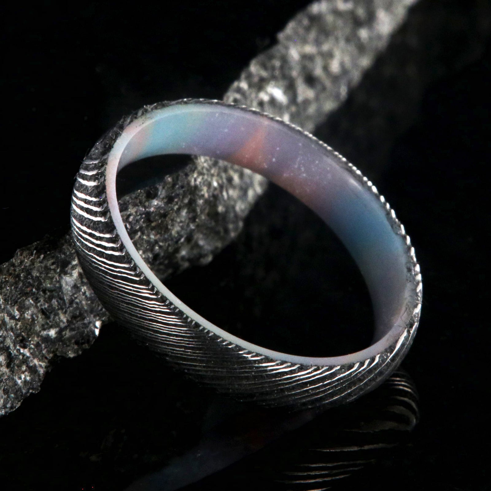 4mm wide black Damascus steel ring with a rounded profile and a glittering rainbow sleeve