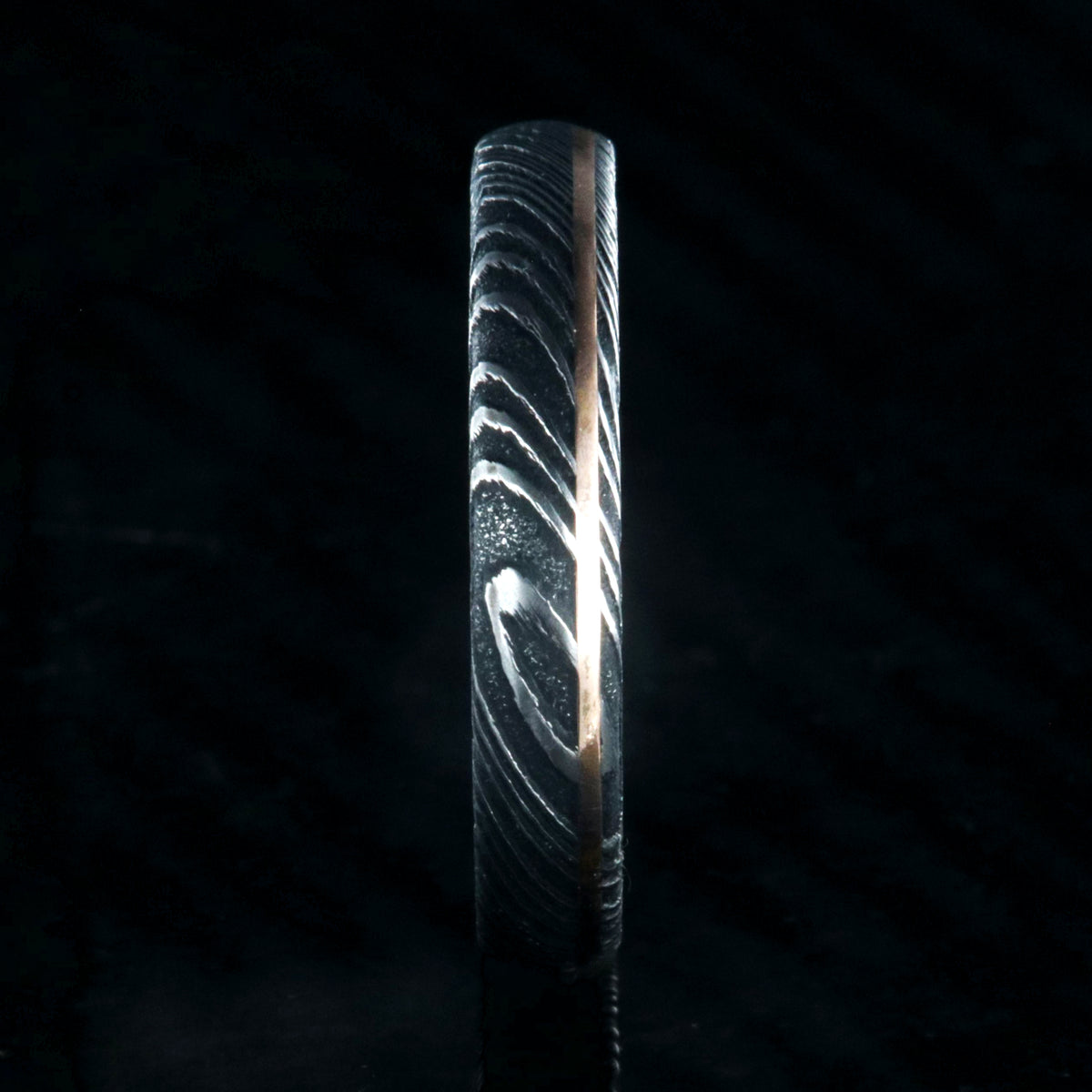 4mm wide black Damascus steel ring with ultra thin rose gold off-center inlay with polished inside