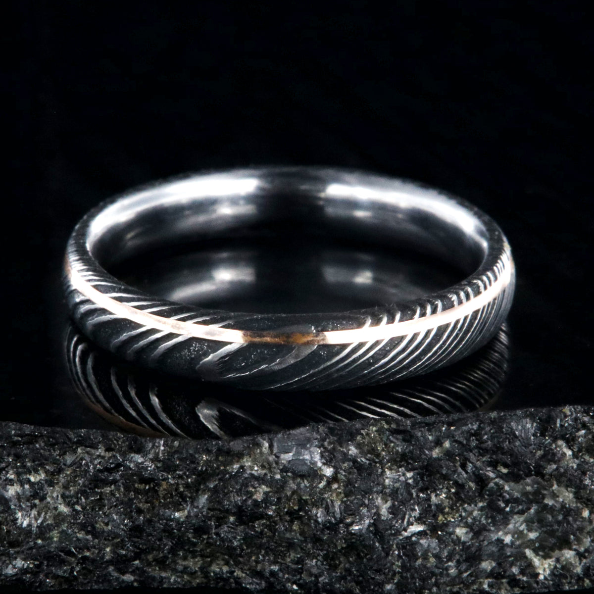 4mm wide black Damascus steel ring with ultra thin rose gold off-center inlay with polished inside