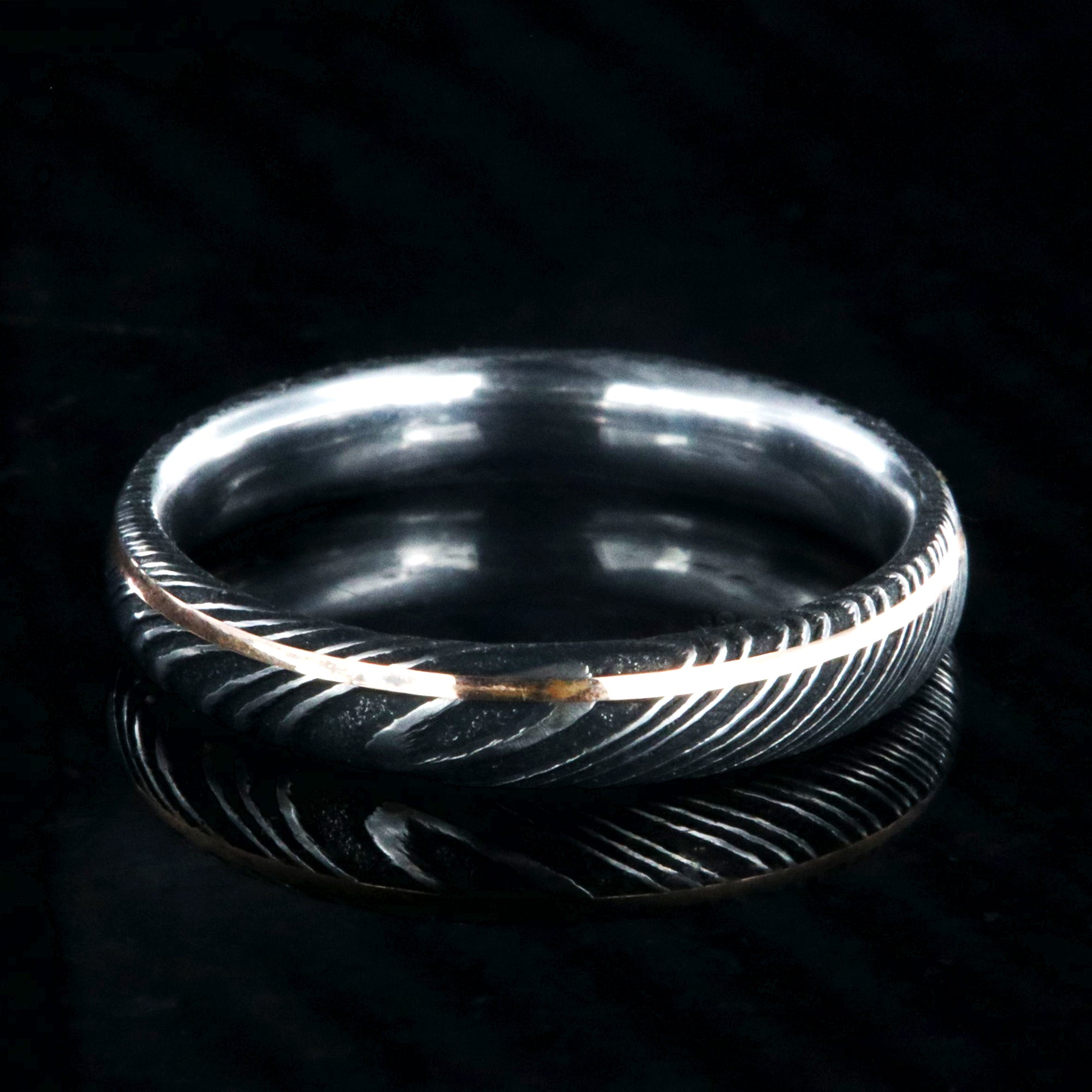 4mm wide black Damascus steel ring with ultra thin rose gold off-center inlay with polished inside
