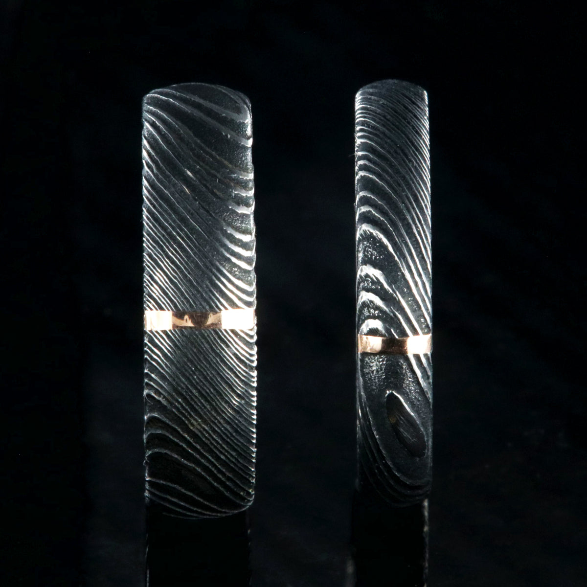 A matching set of Damascus steel wedding ring with a 6mm and 4mm wide bands with a single vertical rose gold inlay