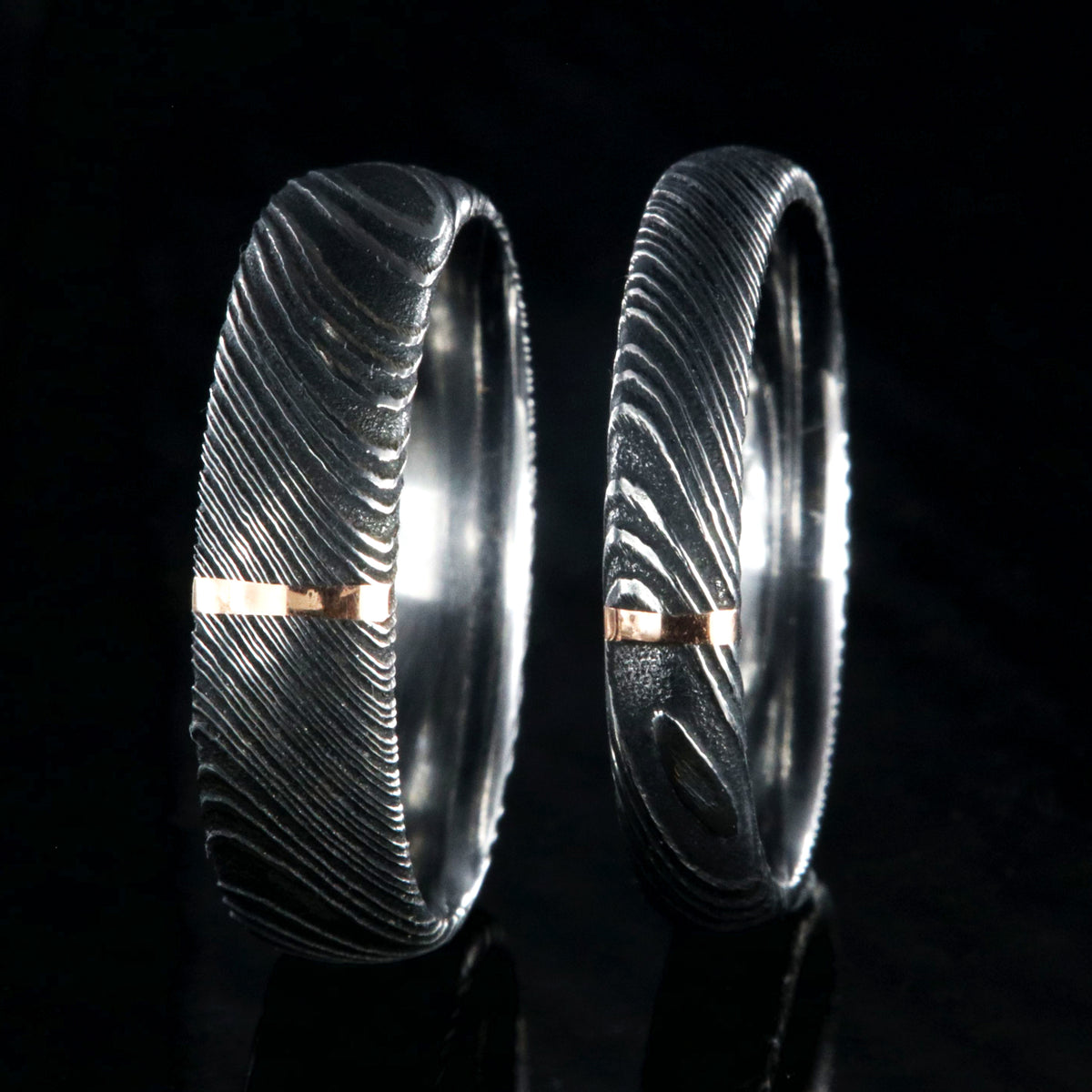 A matching set of Damascus steel wedding ring with a 6mm and 4mm wide bands with a single vertical rose gold inlay