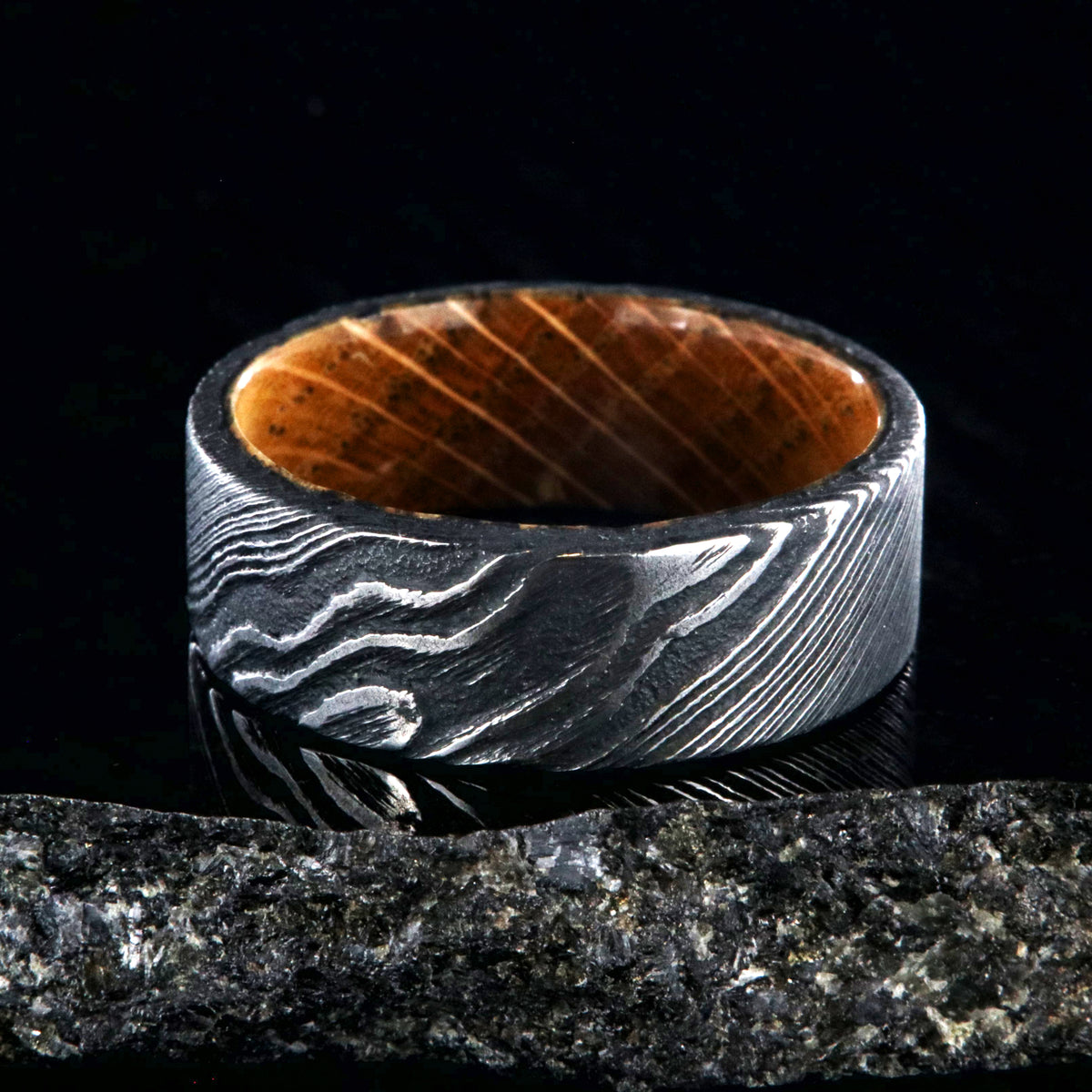8mm wide black Damascus steel ring with flat profile and a Jack Daniel&#39;s whiskey barrel sleeve