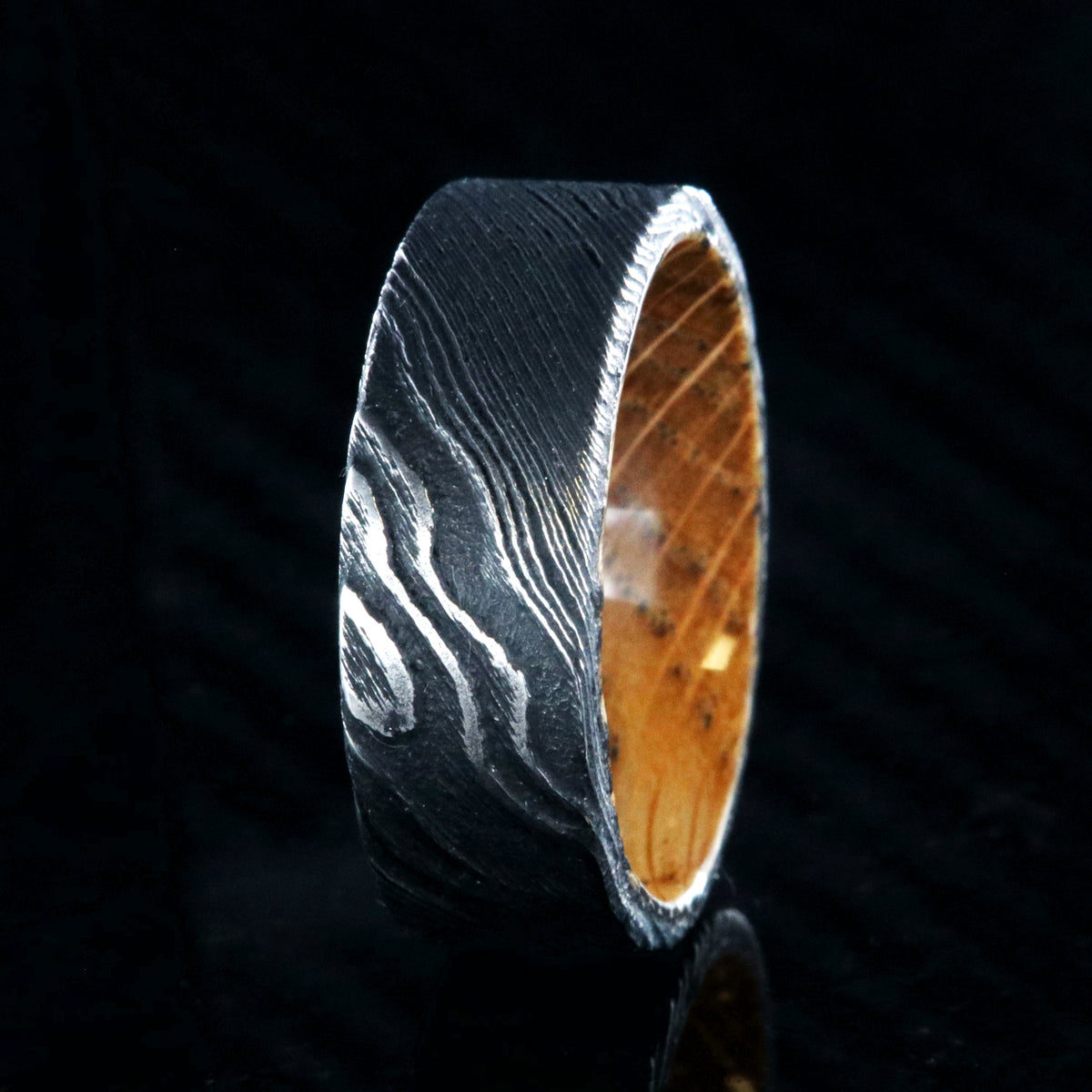 8mm wide black Damascus steel ring with flat profile and a Jack Daniel&#39;s whiskey barrel sleeve