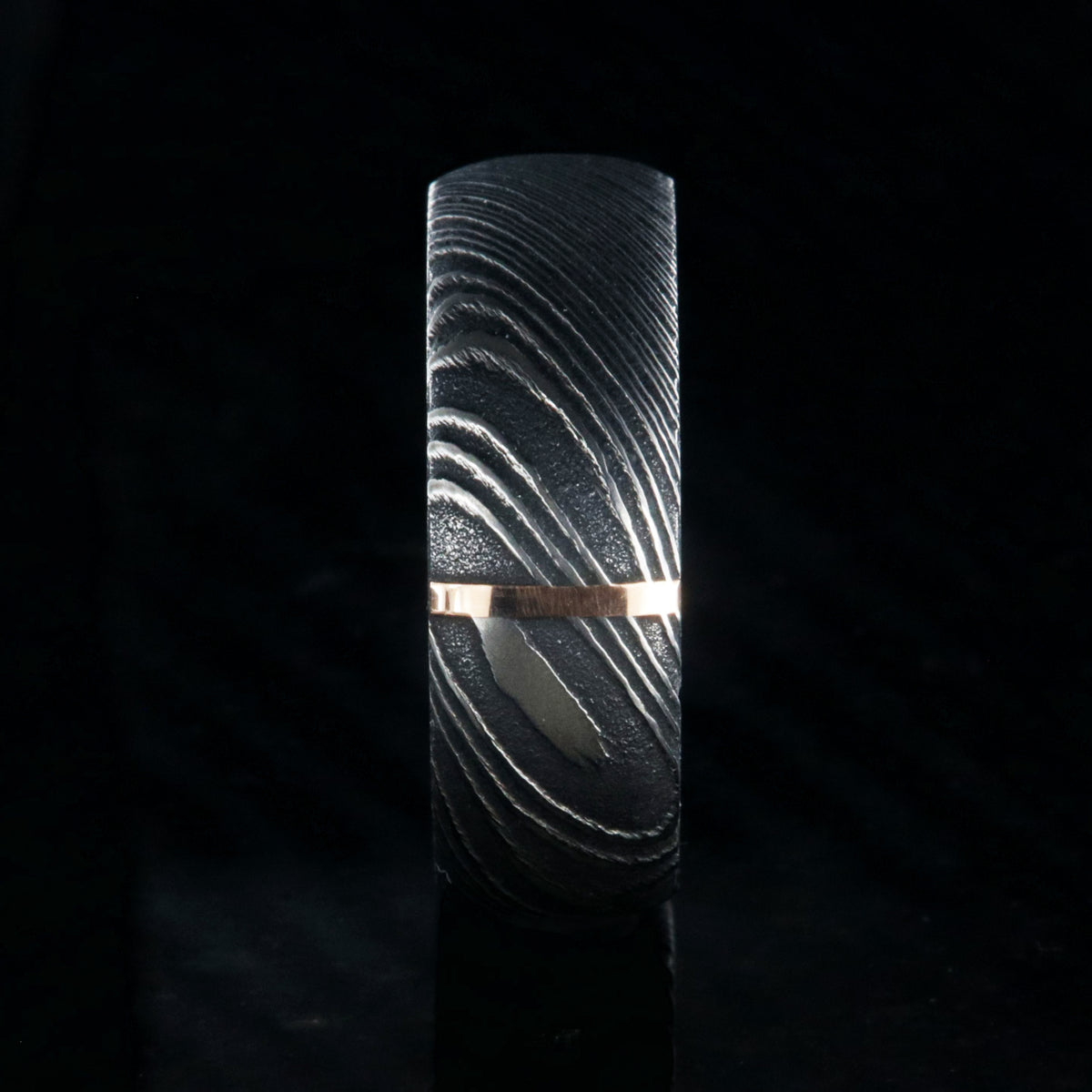 8mm wide black Damascus steel wedding band with a vertical groove of solid 14k rose gold