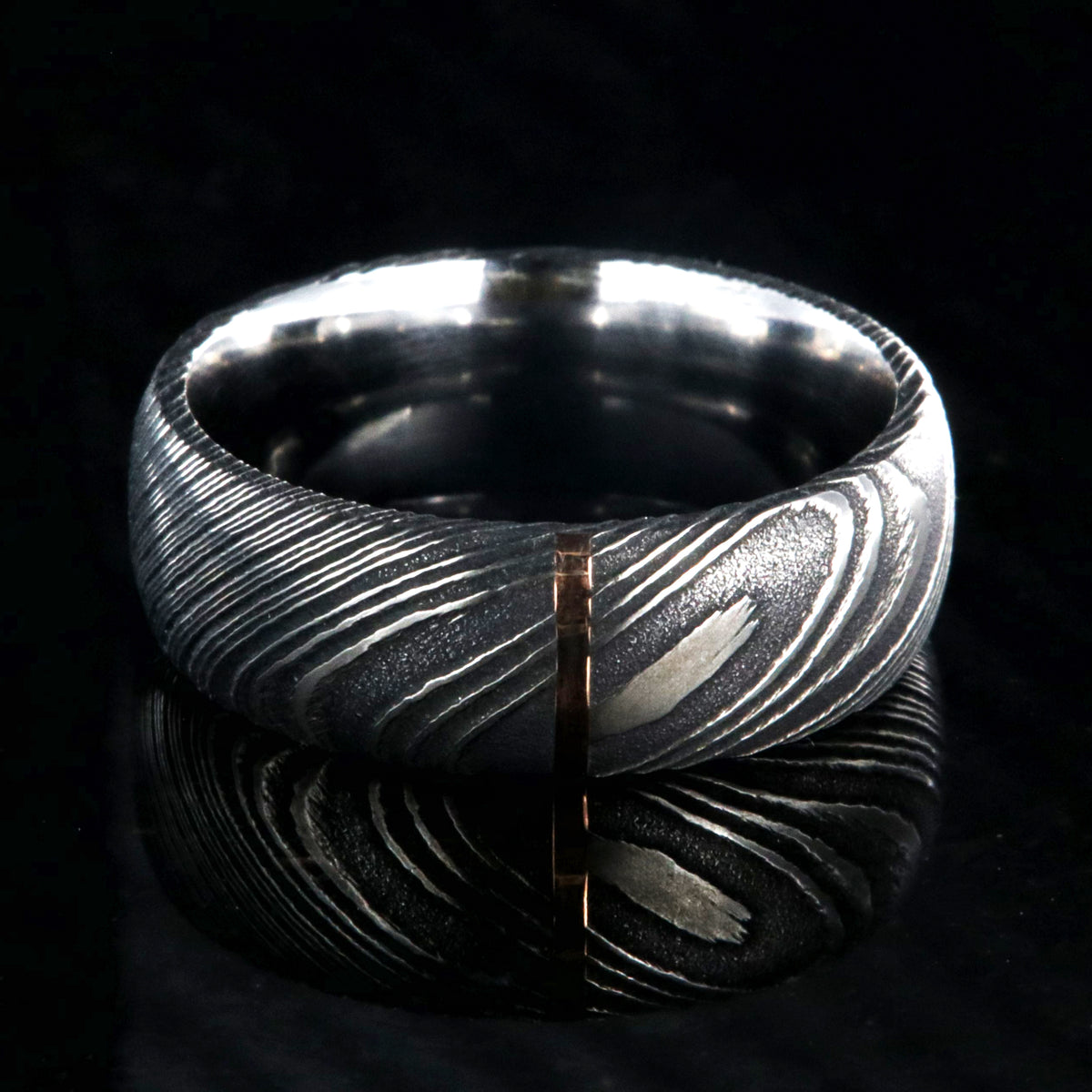 8mm wide black Damascus steel wedding band with a vertical groove of solid 14k rose gold