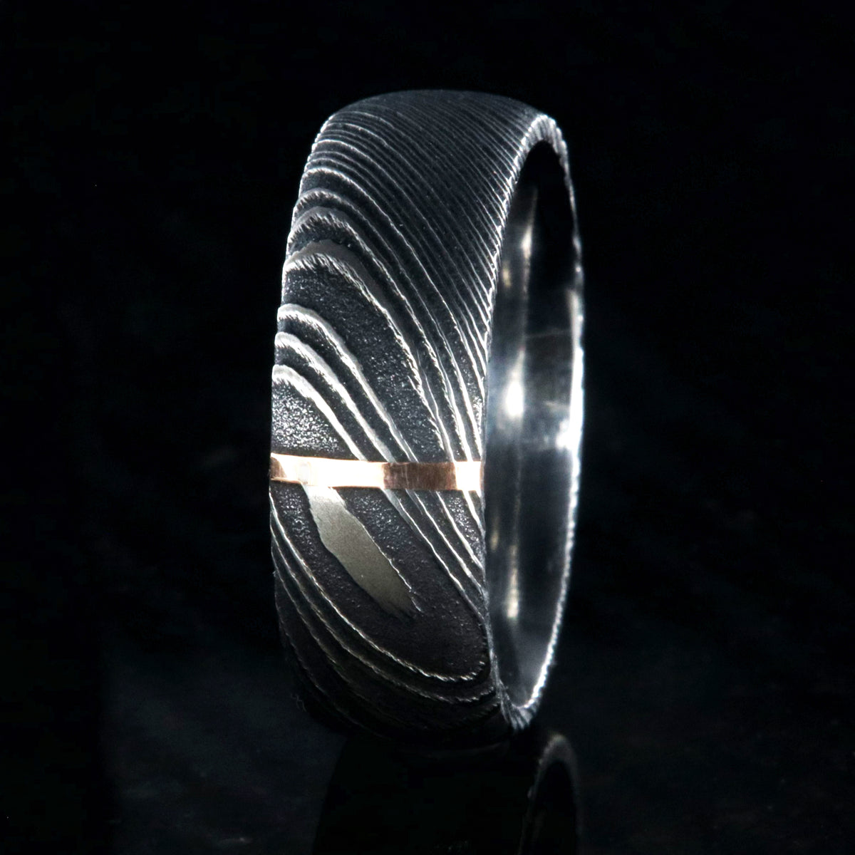 8mm wide black Damascus steel wedding band with a vertical groove of solid 14k rose gold