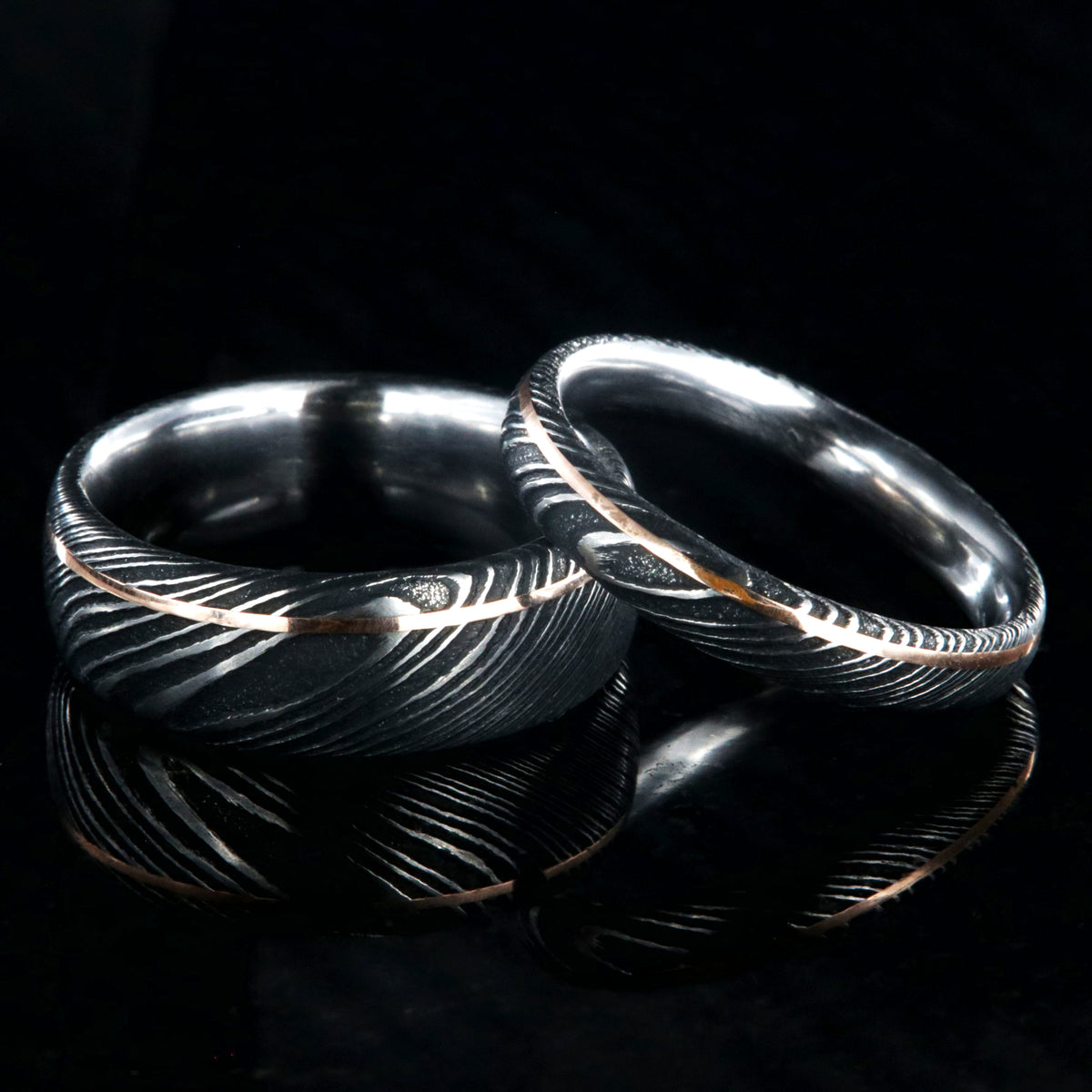 8mm and 4mm wide matching Damascus steel wedding bands with ultra-thin off-centered rose gold inlays