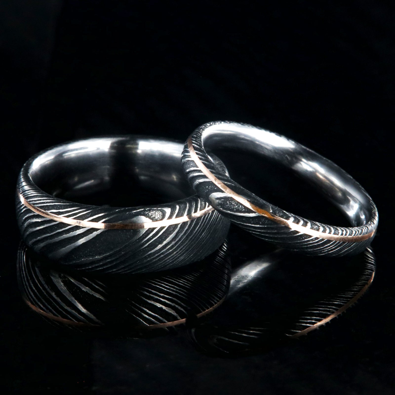 8mm and 4mm wide matching Damascus steel wedding bands with ultra-thin off-centered rose gold inlays