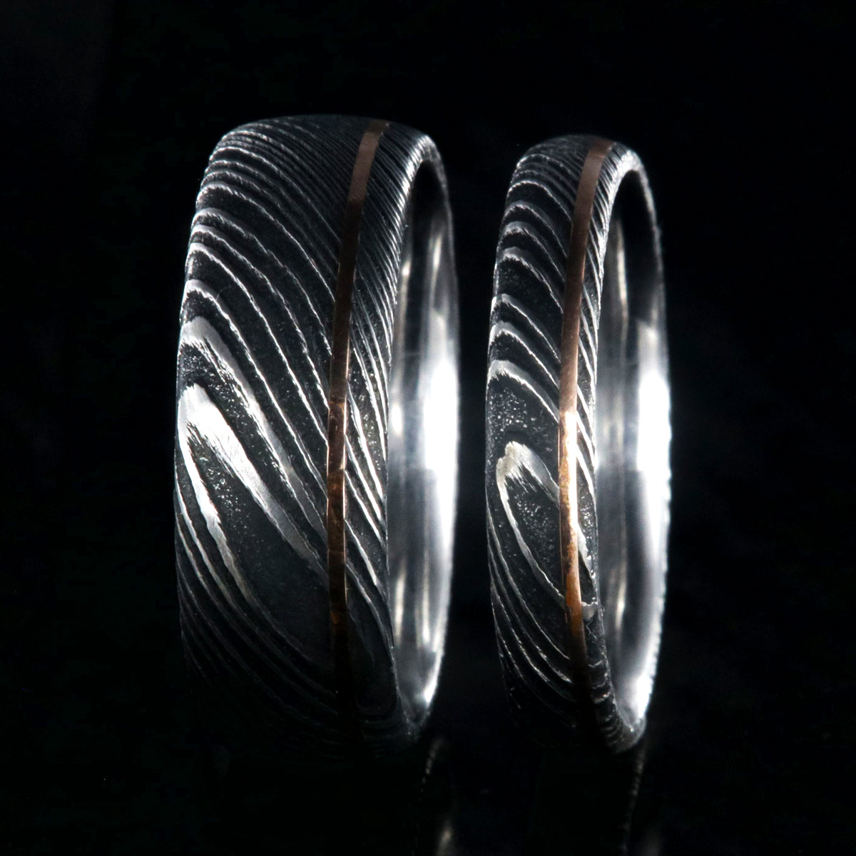8mm and 4mm wide matching Damascus steel wedding bands with ultra-thin off-centered rose gold inlays