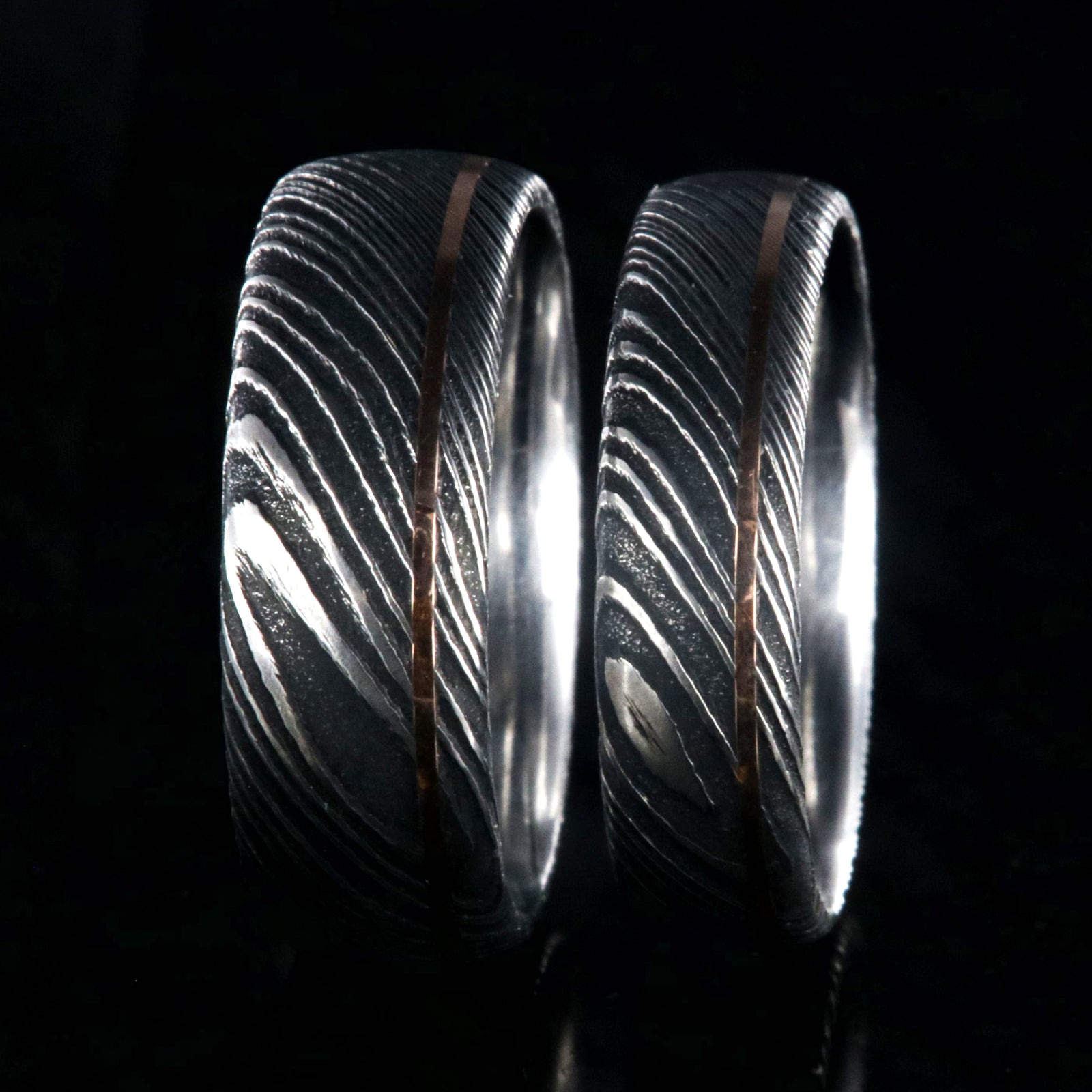 8mm and 6mm wide black Damascus steel matching wedding band set with ultra-thin off-centered rose gold inlay