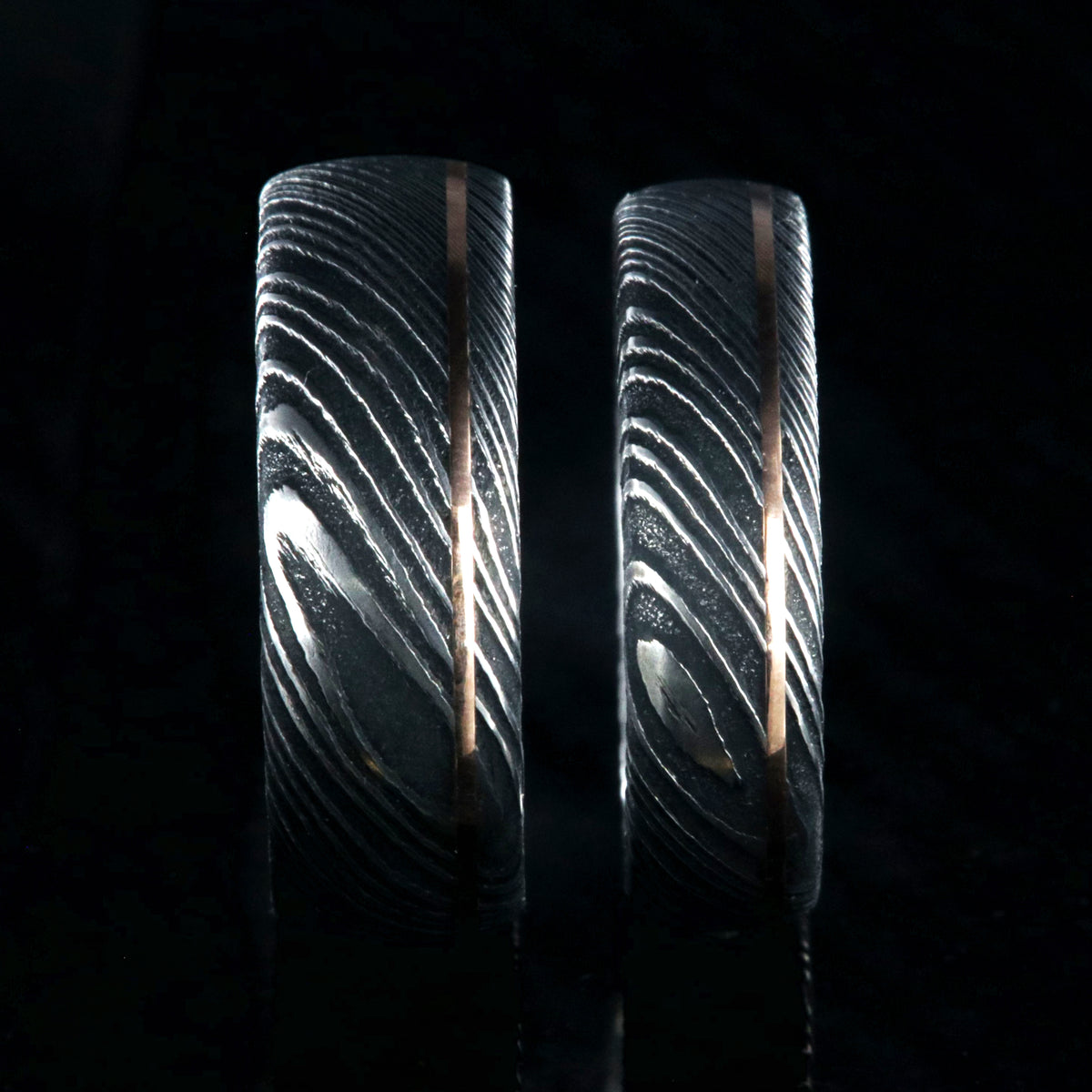 8mm and 6mm wide black Damascus steel matching wedding band set with ultra-thin off-centered rose gold inlay