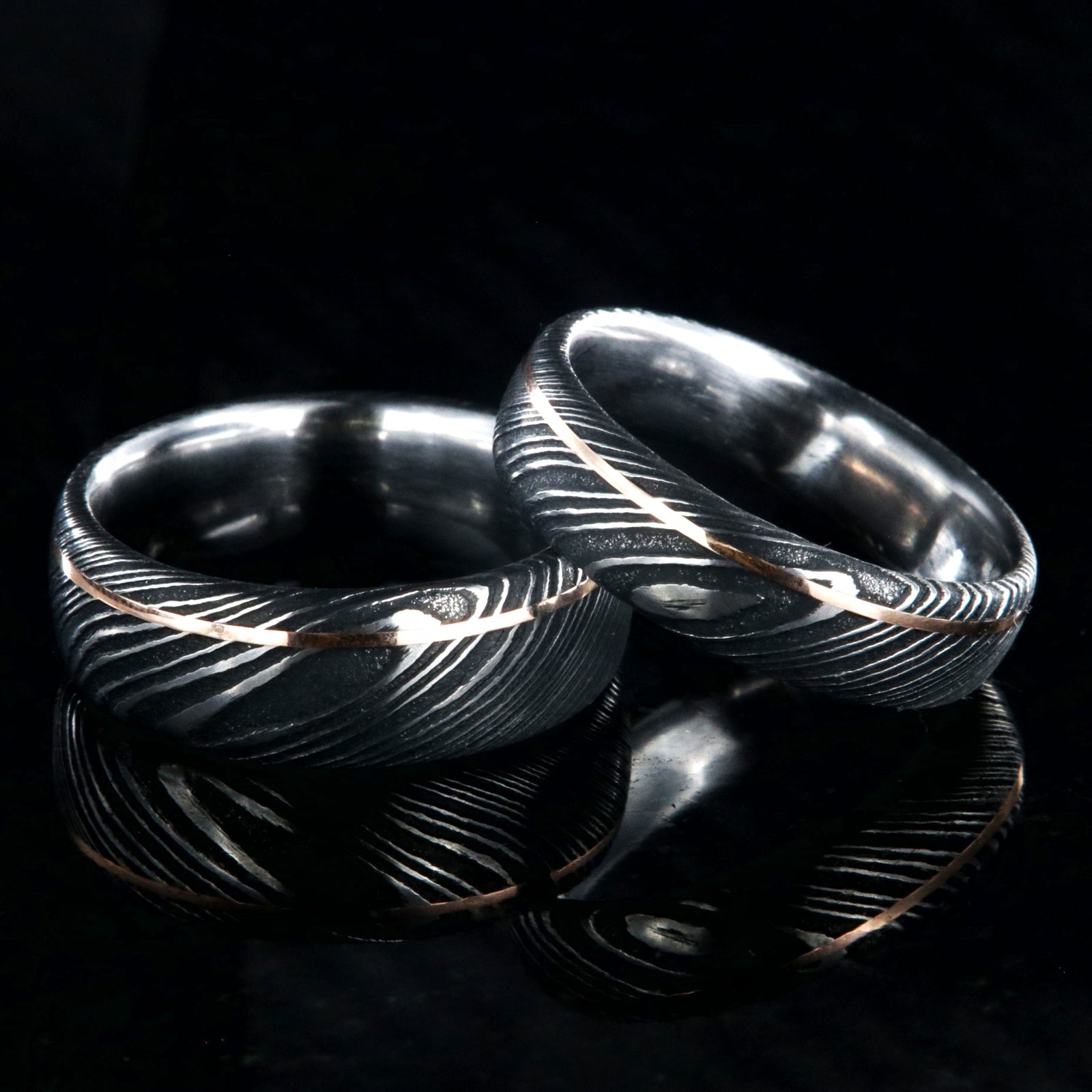 8mm and 6mm wide black Damascus steel matching wedding band set with ultra-thin off-centered rose gold inlay