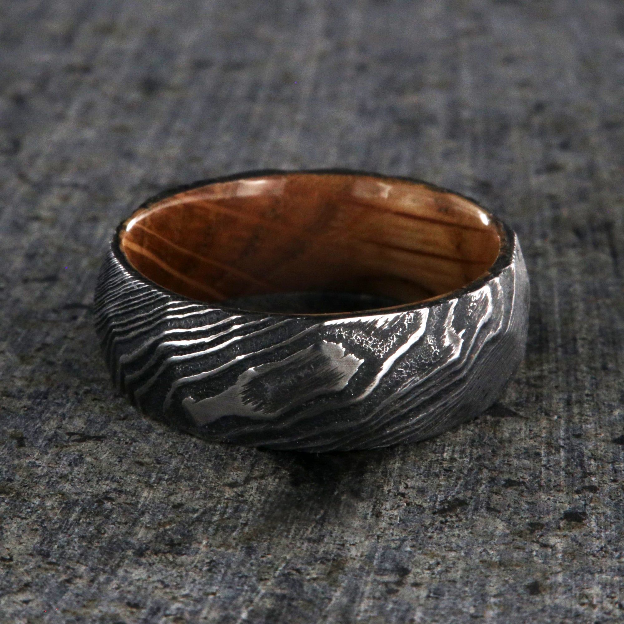 8mm wide big hammered texture on a Damascus steel wedding ring with a whiskey barrel sleeve