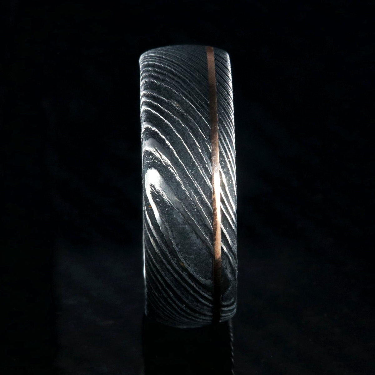 8mm wide black Damascus steel wedding band with an ultra-thin rose gold inlay
