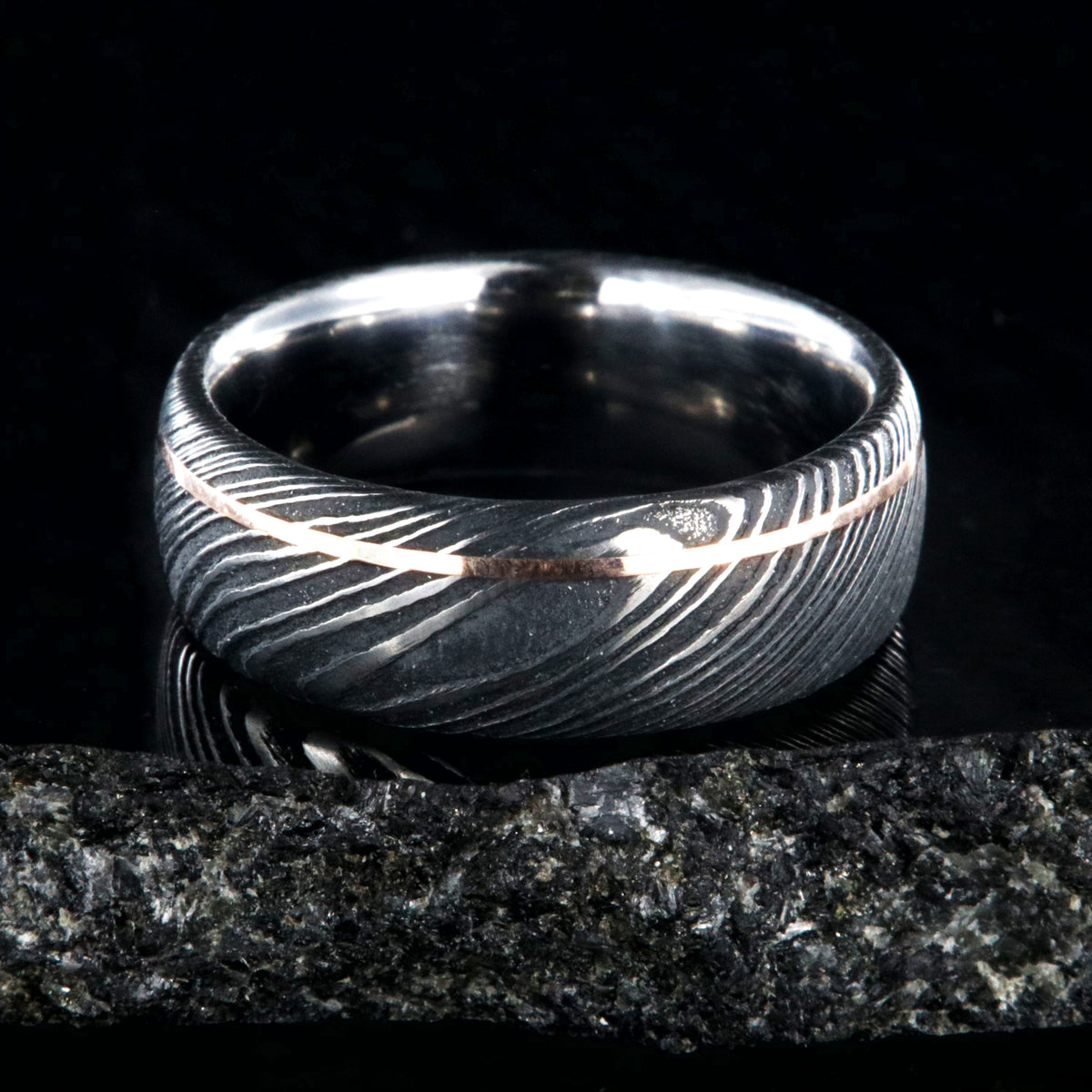 8mm wide black Damascus steel wedding band with an ultra-thin rose gold inlay