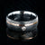 8mm wide black Damascus steel ring with rounded profile, polished inside, an off-center rose gold inlay and 3mm round bezel set diamond