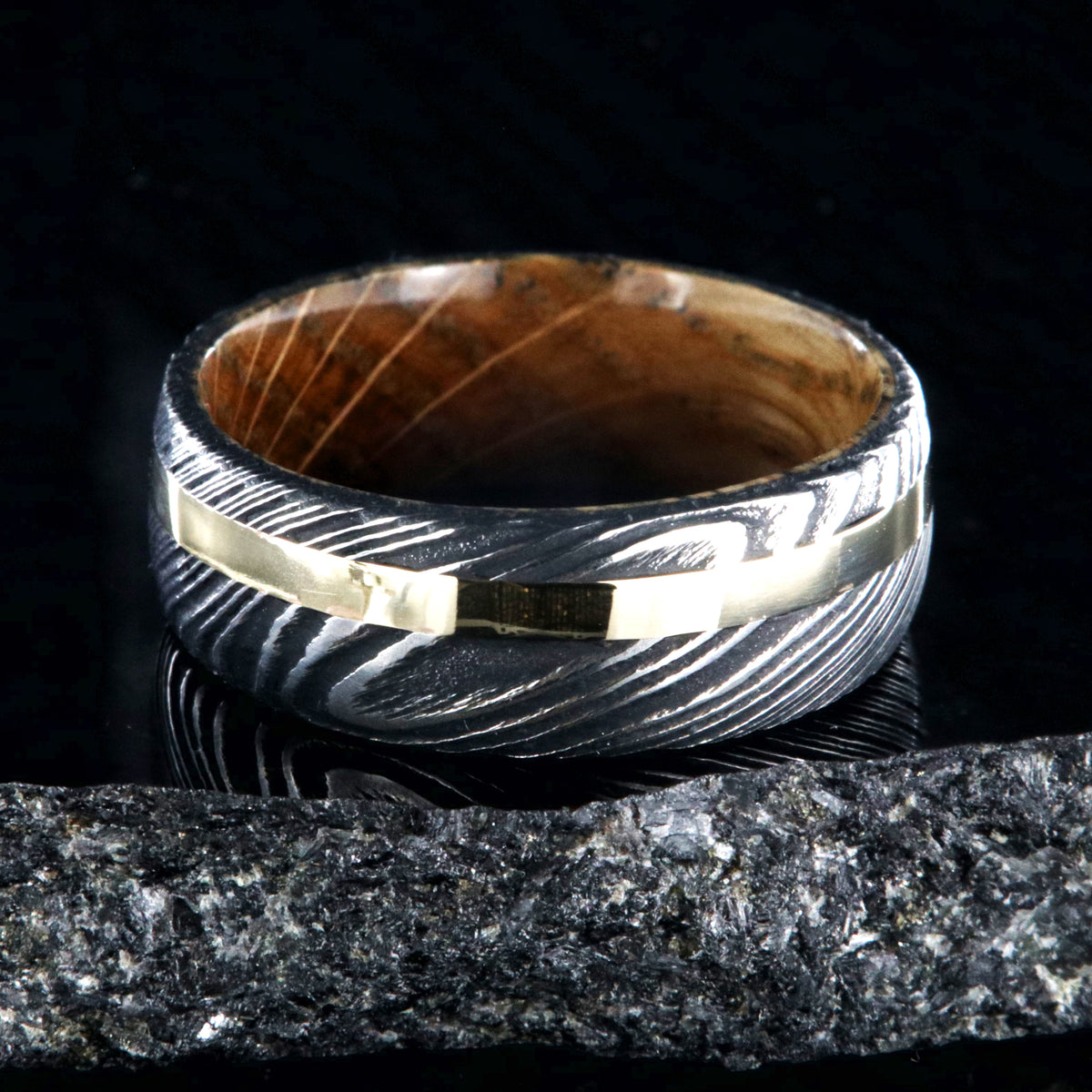 8mm wide black Damascus steel wedding ring with rounded profile, 2mm wide yellow gold inlay and a Jack Daniel&#39;s whiskey barrel sleeve