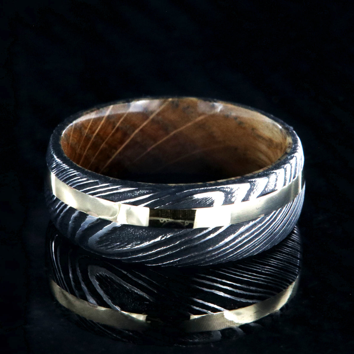 8mm wide black Damascus steel wedding ring with rounded profile, 2mm wide yellow gold inlay and a Jack Daniel&#39;s whiskey barrel sleeve