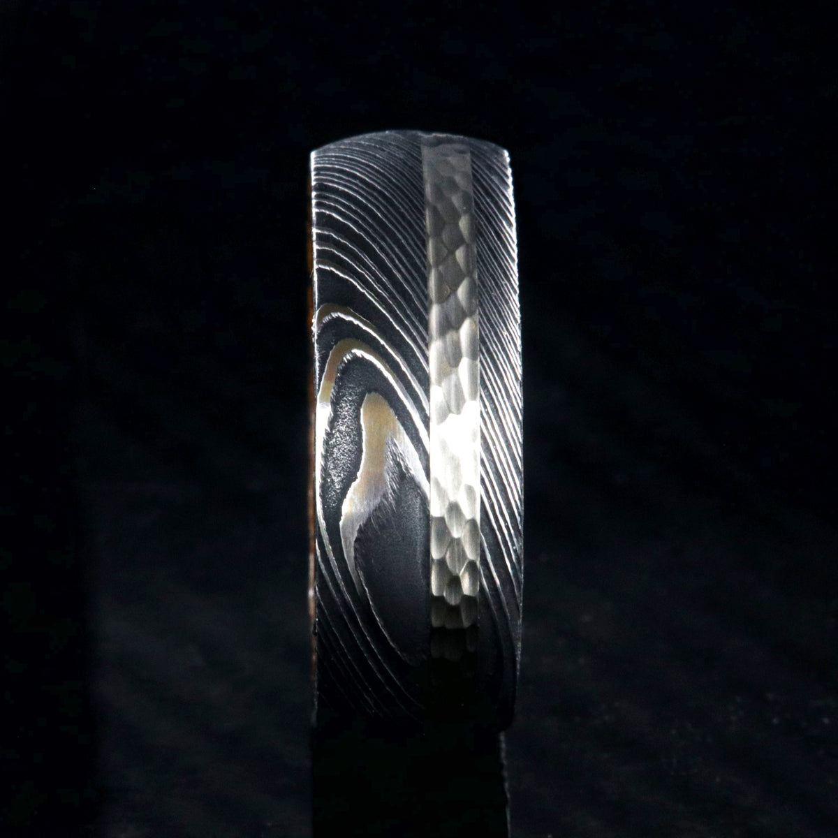 8mm wide black Damascus steel ring with a 2mm wide hammered white gold inlay and a whiskey barrel sleeve