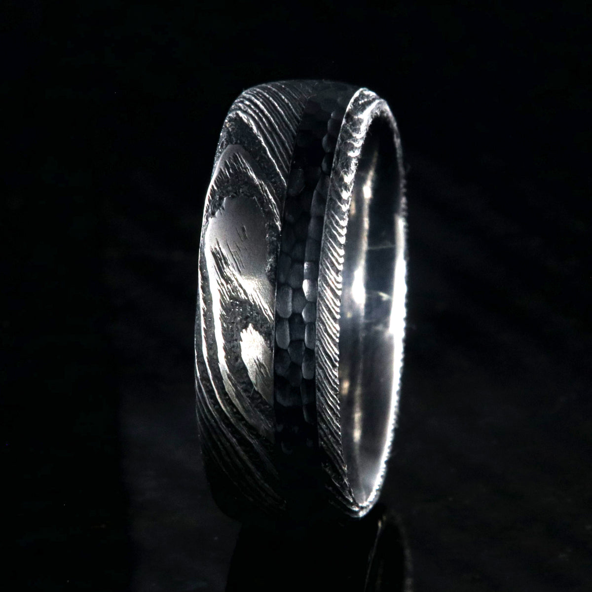 8mm wide black Damascus steel wedding ring with rounded profile, polished inside, and hammered black titanium inlay