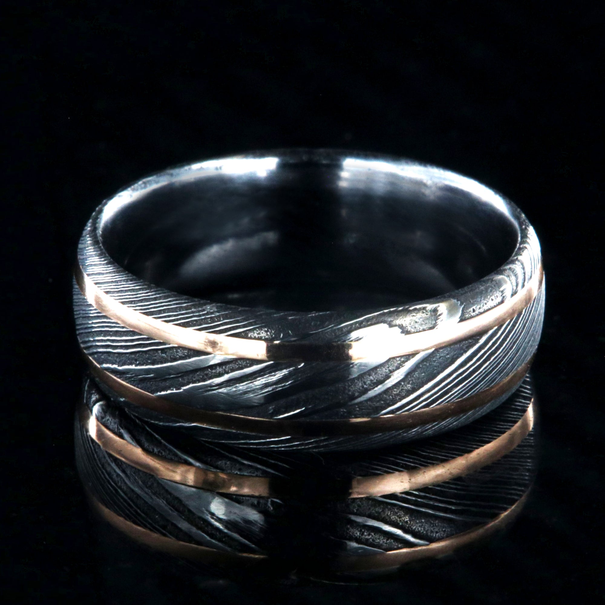 8mm wide black Damascus steel wedding ring with two thin edge rose gold  inlays and polished inside