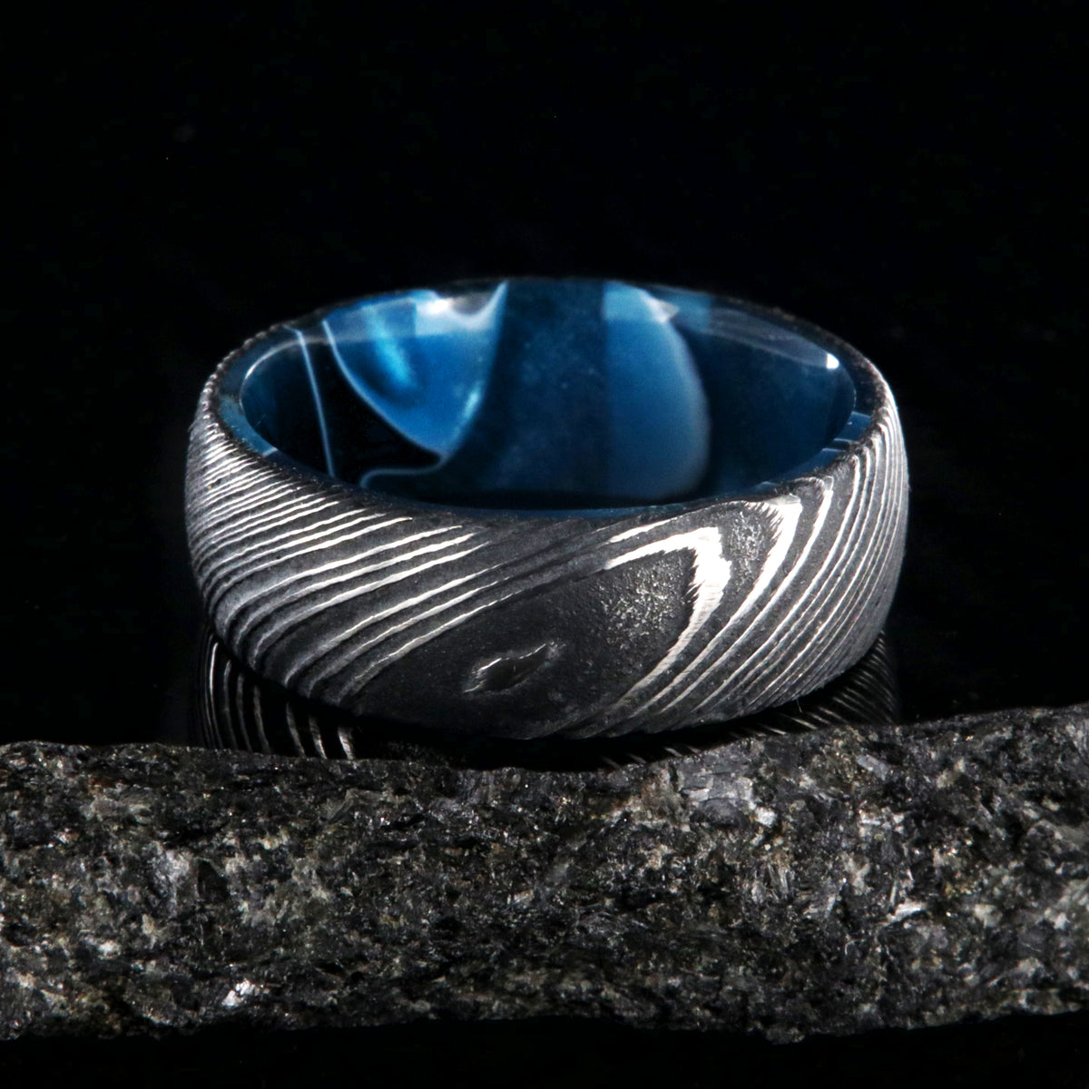 7mm wide black Damascus steel wedding band with an ocean blue sleeve and rounded profile