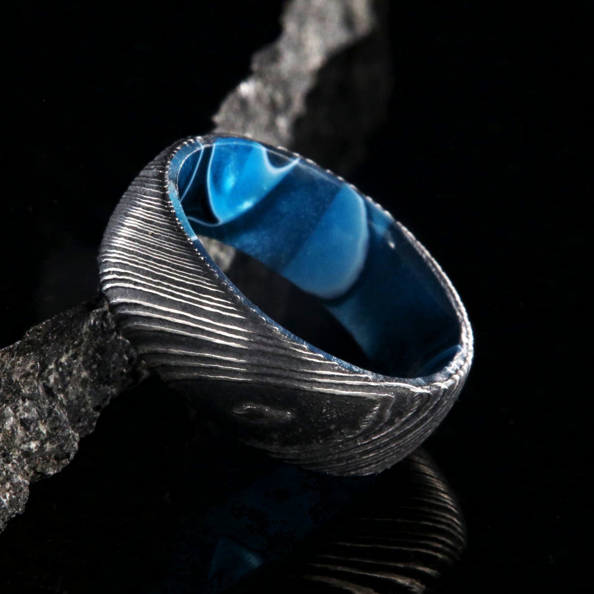 7mm wide black Damascus steel wedding band with an ocean blue sleeve and rounded profile