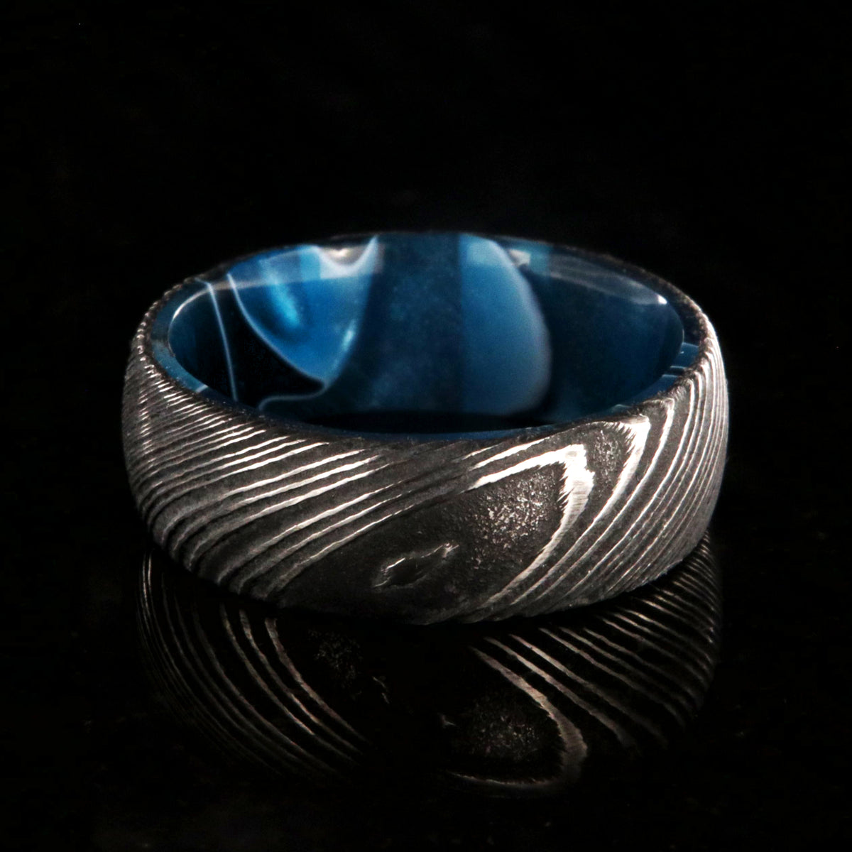 7mm wide black Damascus steel wedding band with an ocean blue sleeve and rounded profile