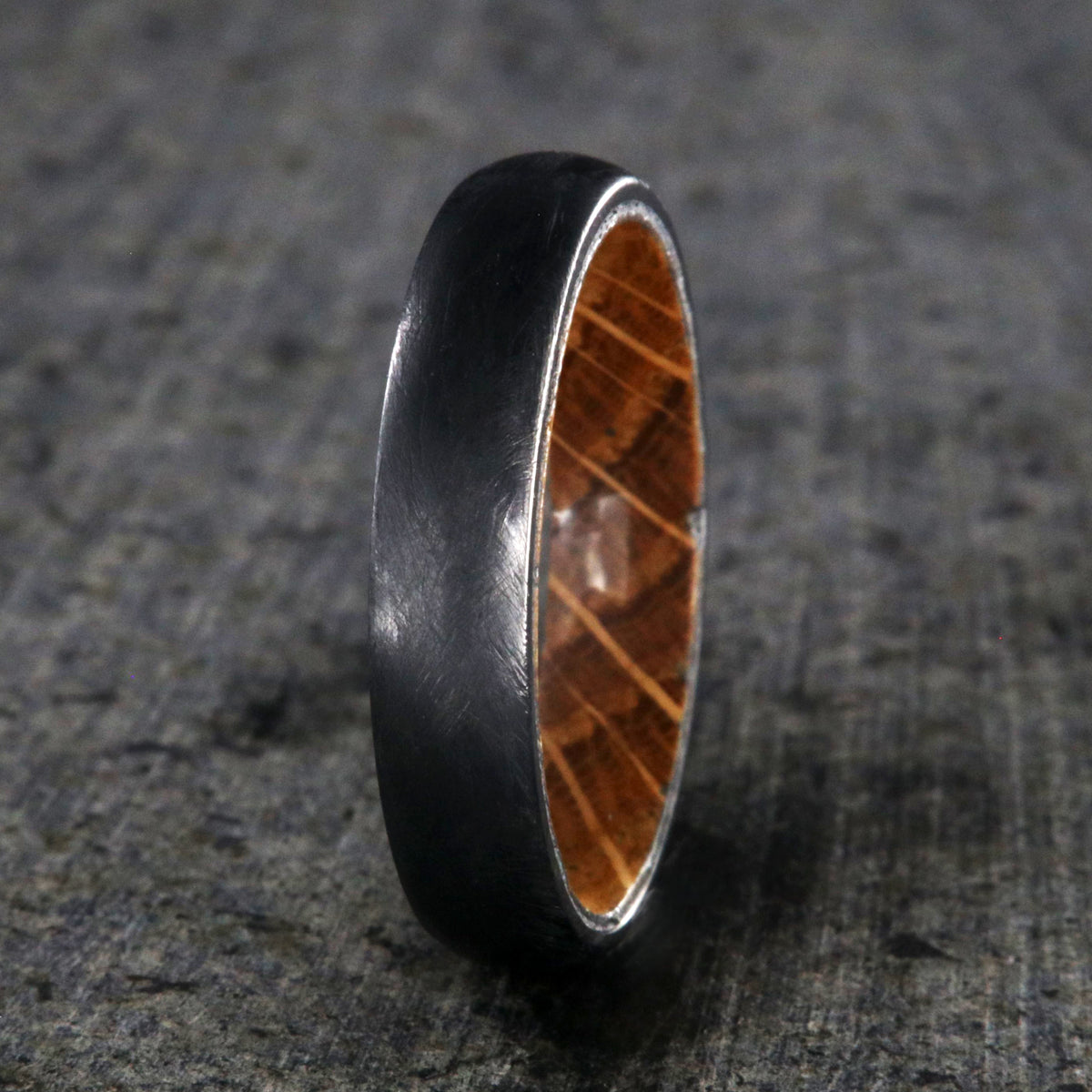 5mm wide black titanium wedding band with a distressed finish, rounded profile, and whiskey barrel sleeve