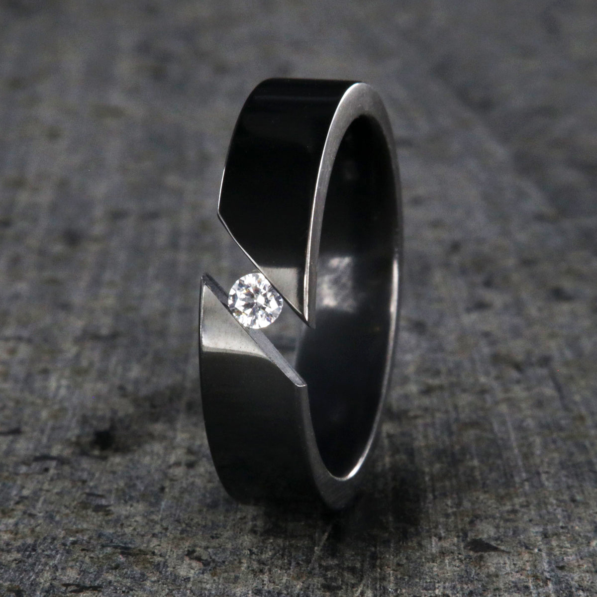6mm wide black zirconium tension set ring with 3mm round gemstone and diagonal tension
