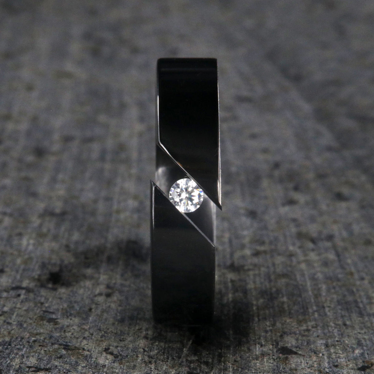 6mm wide black zirconium tension set ring with 3mm round gemstone and diagonal tension