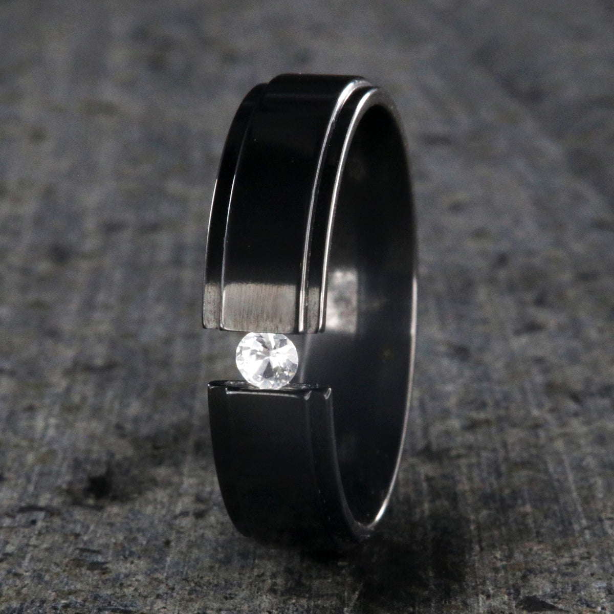 6mm wide black zirconium tension set ring with a 3mm round gemstone