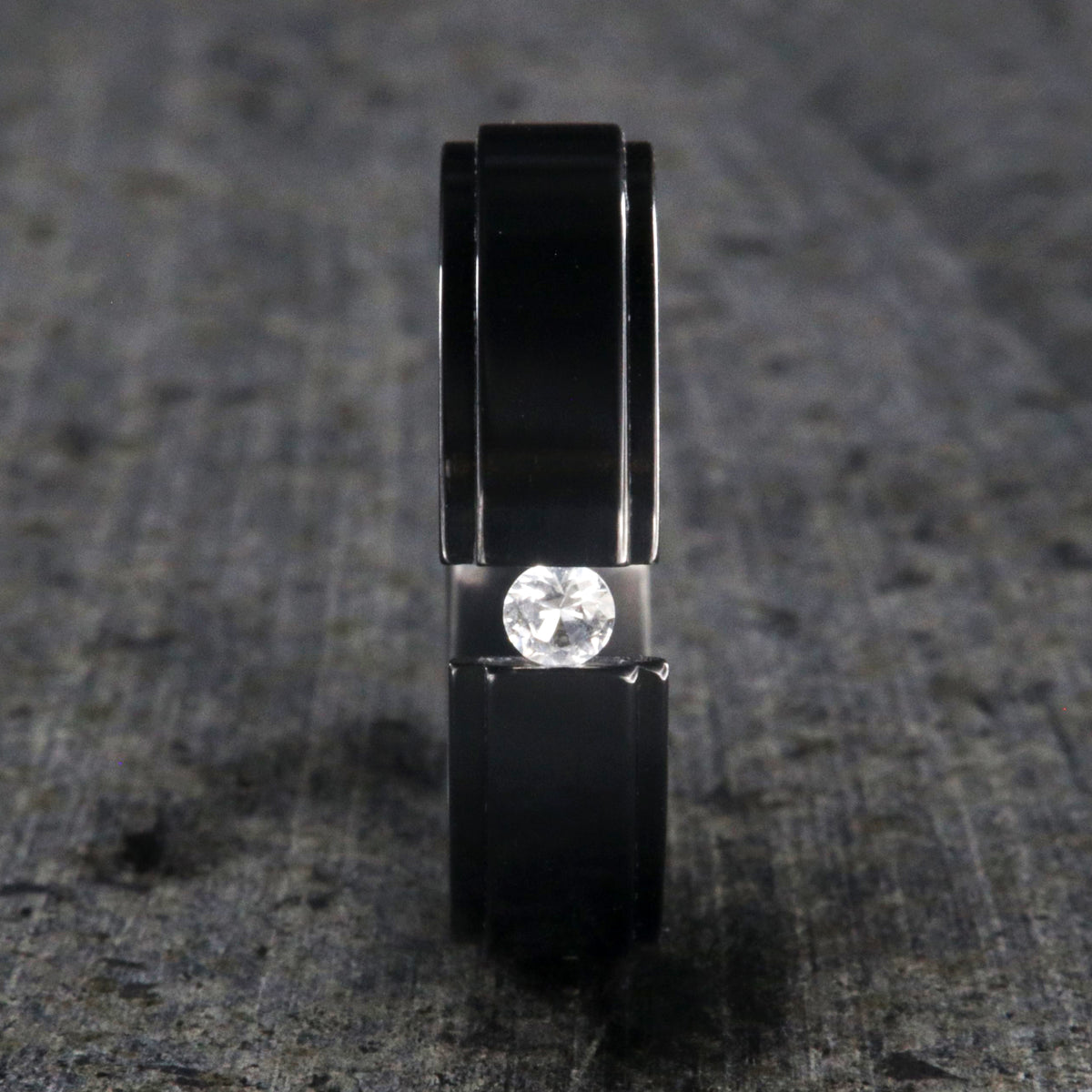 6mm wide black zirconium tension set ring with a 3mm round gemstone