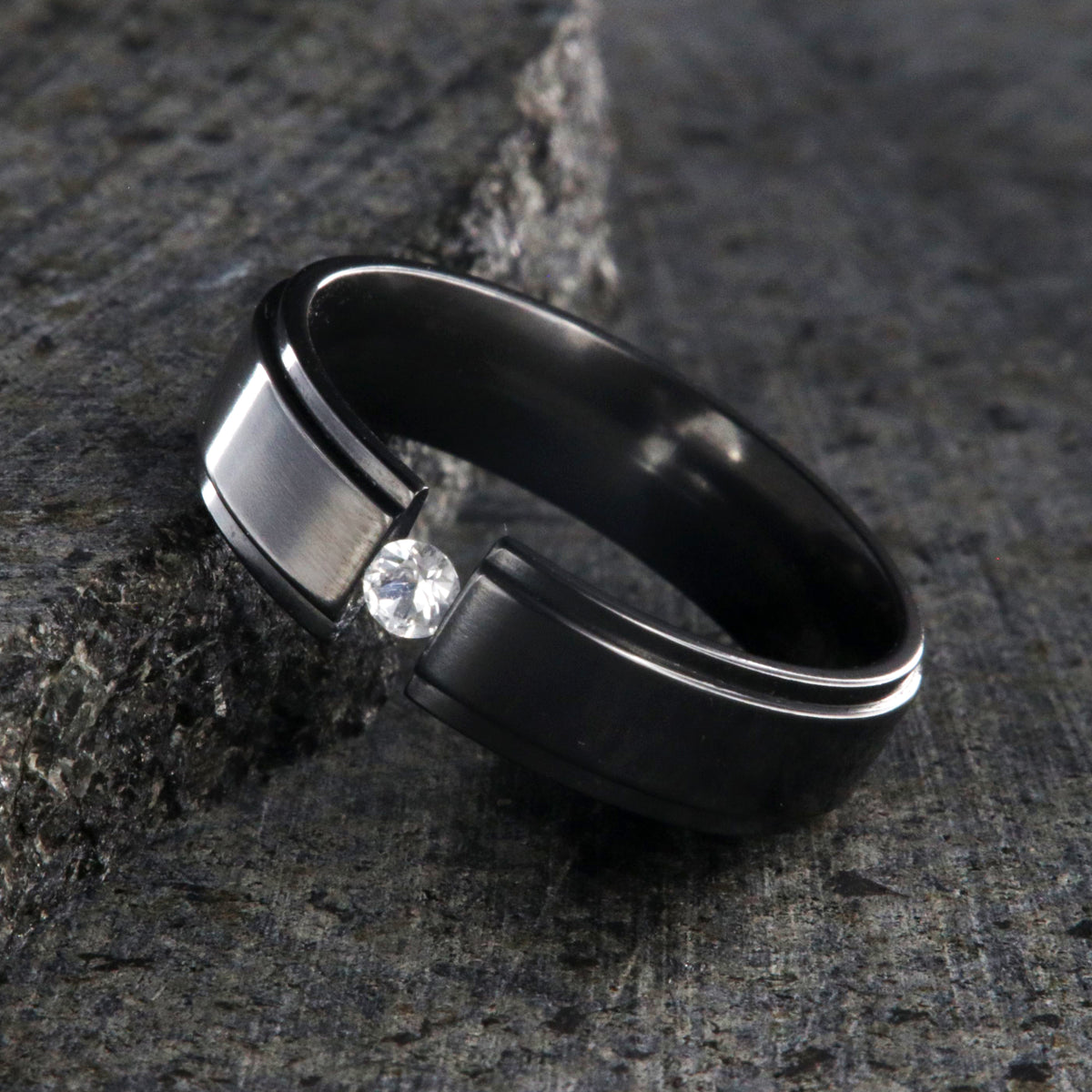6mm wide black zirconium tension set ring with a 3mm round gemstone