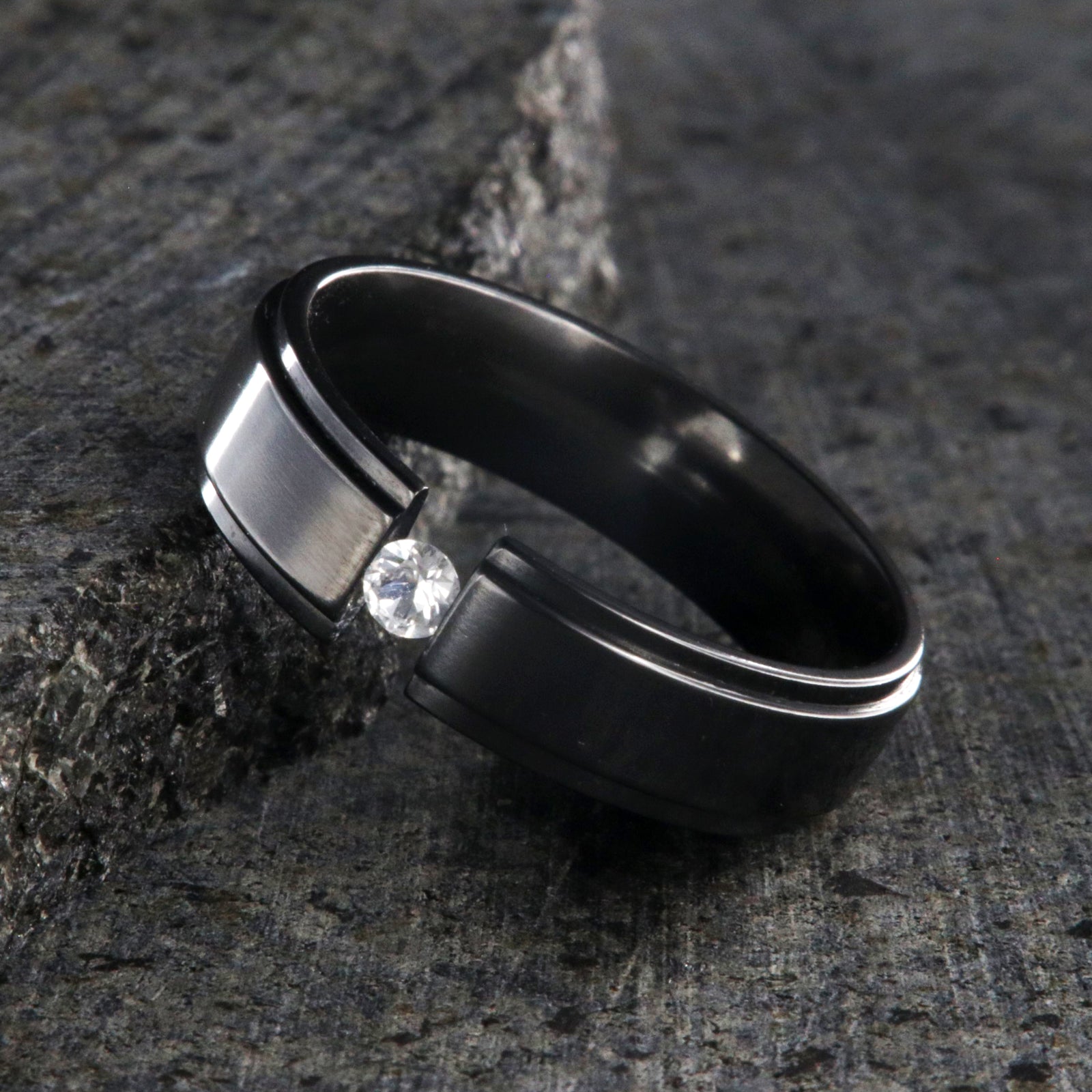6mm wide black zirconium tension set ring with a 3mm round gemstone