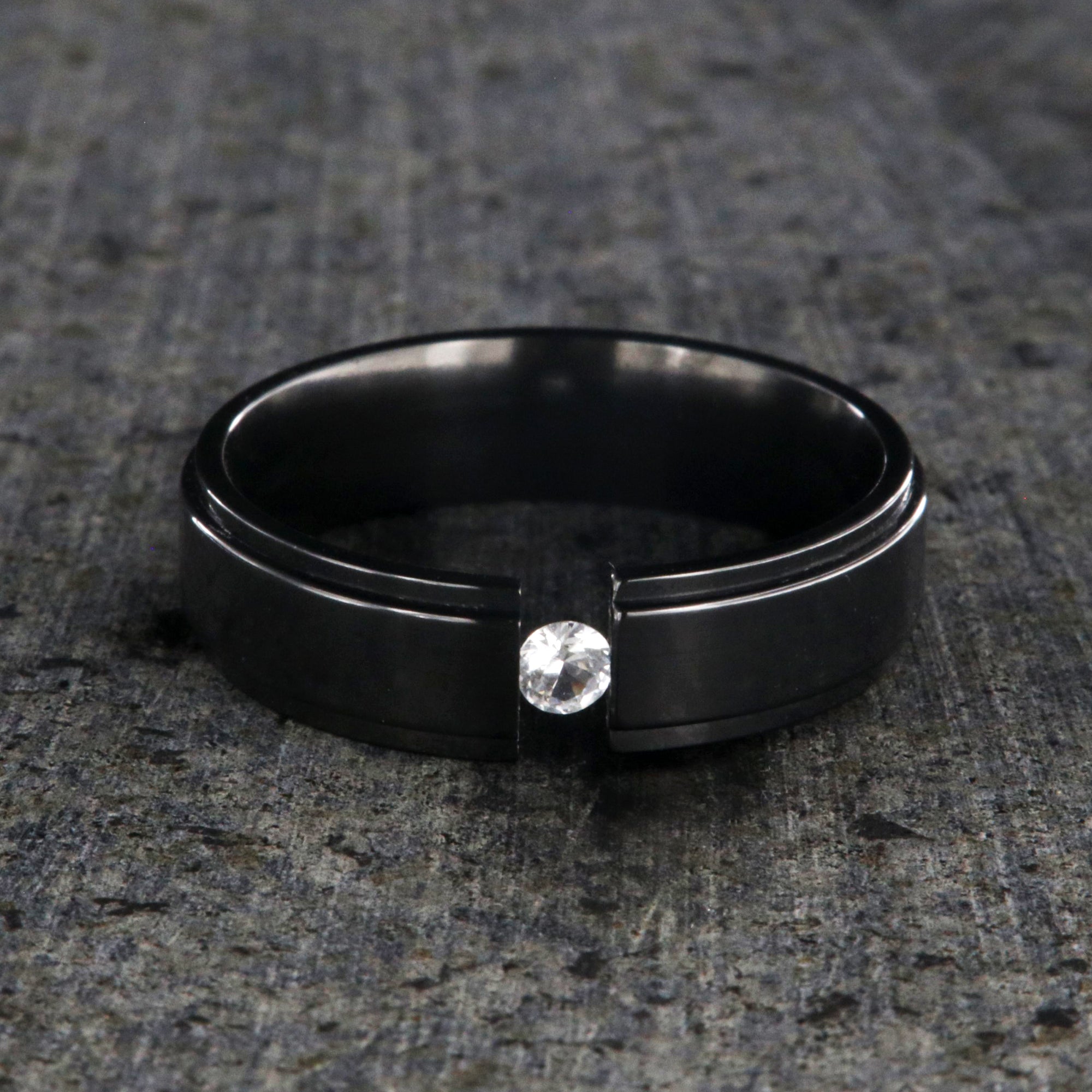 6mm wide black zirconium tension set ring with a 3mm round gemstone