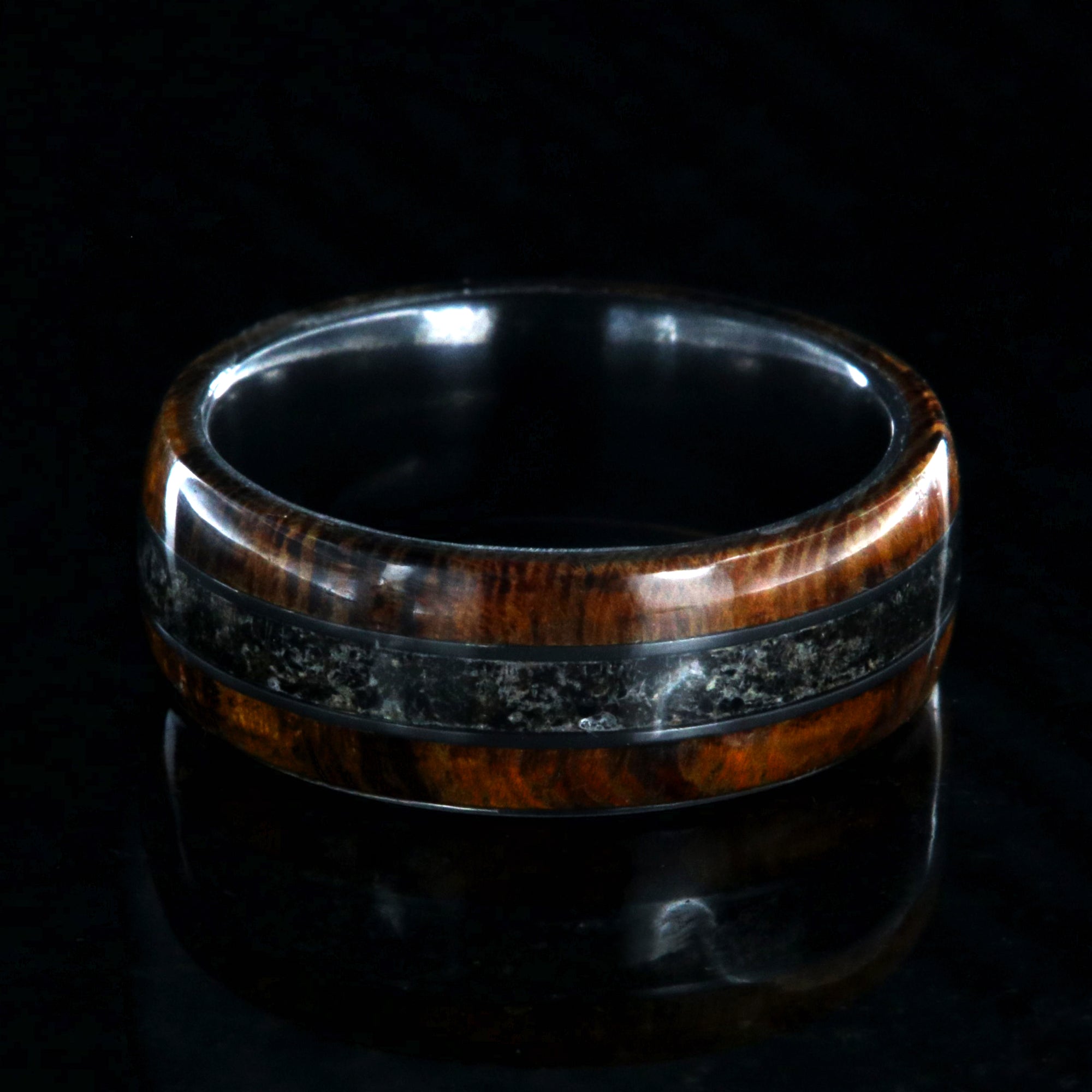 7mm wide men's wedding ring with Arizona ironwood edges and dinosaur bone fossil inlay with a black zirconium sleeve