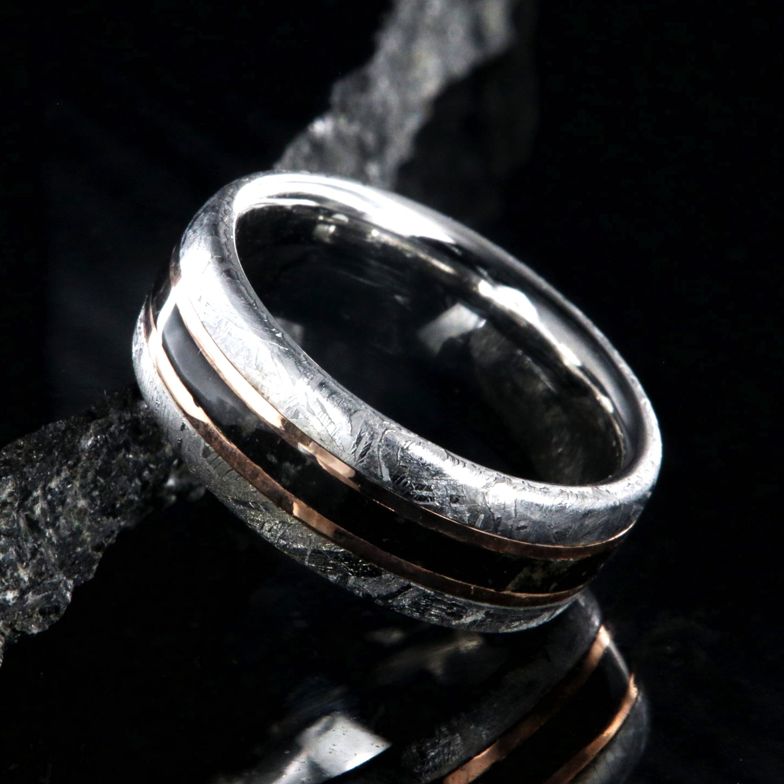 8mm wide men's wedding band with cobalt sleeve and meteorite edges, a dinosaur bone center inlay with rose gold inlays on either side