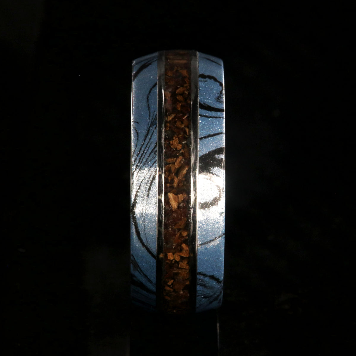 9mm wide ring for men with blue and black cobaltium mokume edges and a dinosaur bone inlay