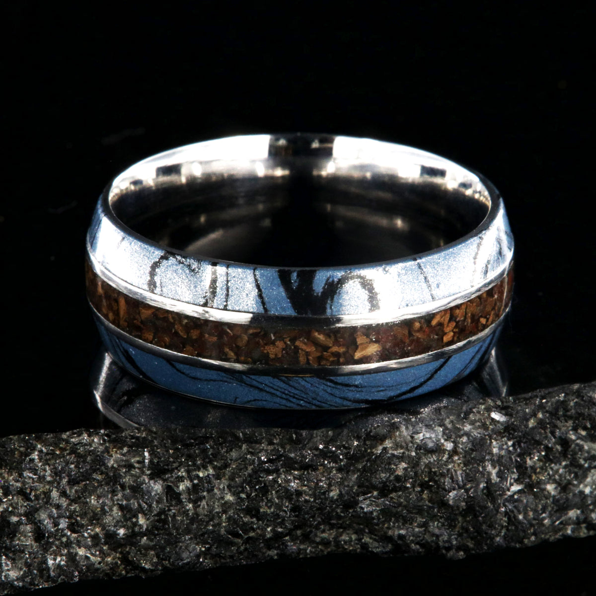 9mm wide ring for men with blue and black cobaltium mokume edges and a dinosaur bone inlay